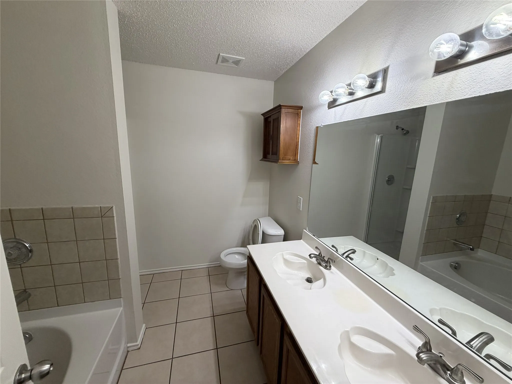 Dual vanity with integrated sinks, full-width mirror, and overhead lighting
