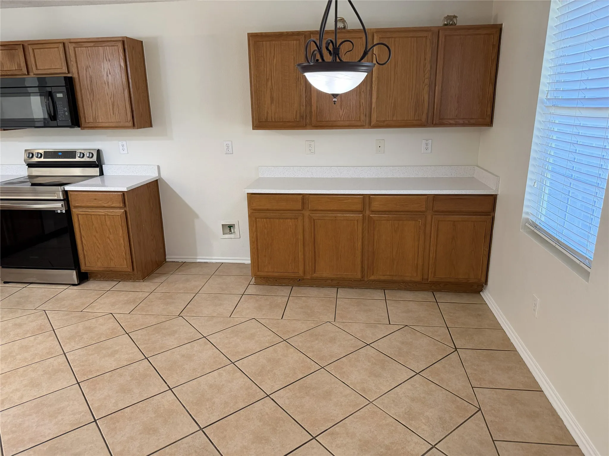 Kitchen featuring wood cabinetry, white countertops, tile flooring, and stainless steel appliances