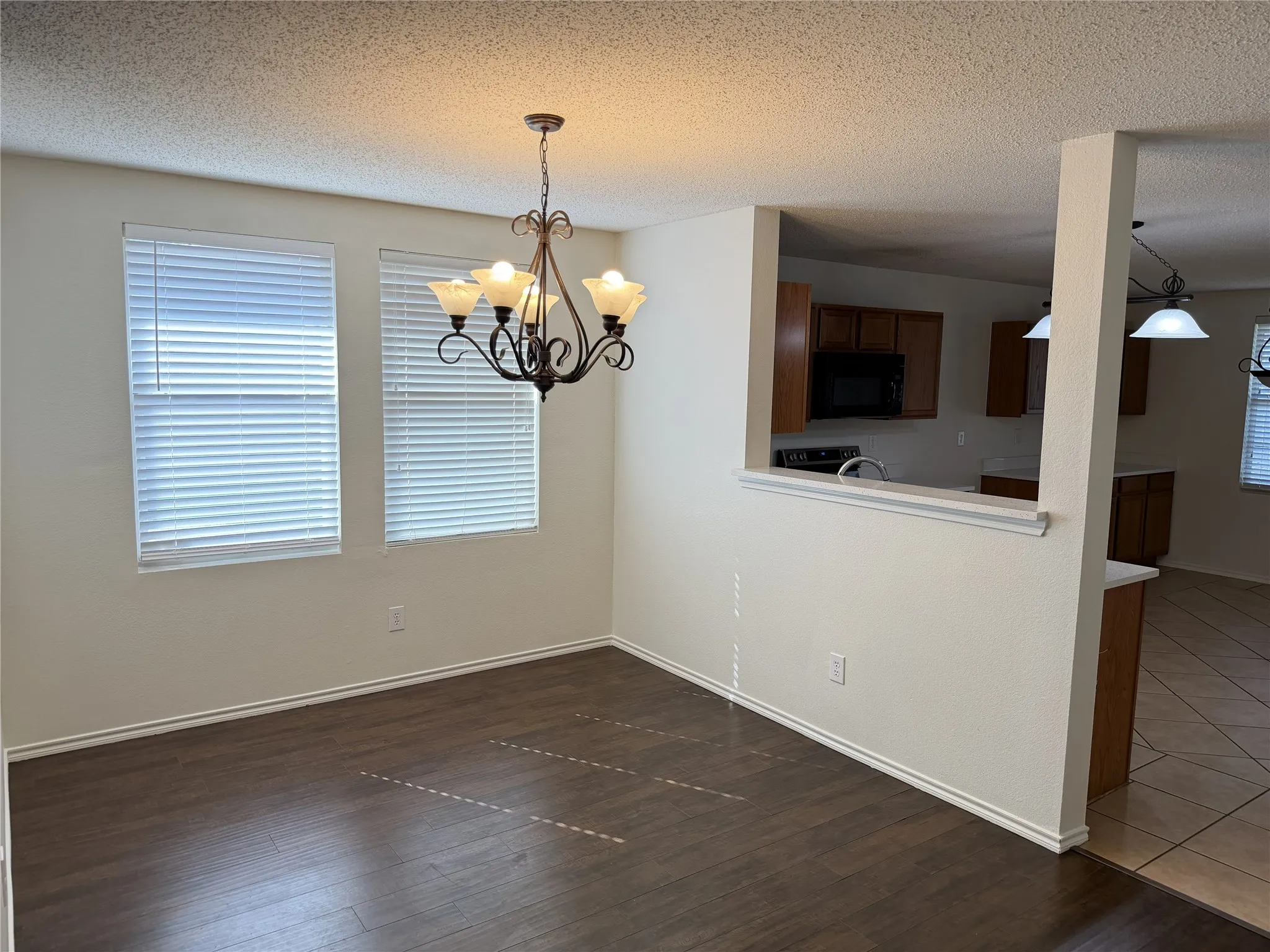 Dining area featuring wood-finish flooring, two large windows, and a decorative chandelier