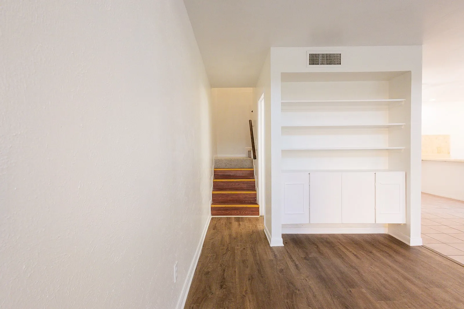 Built-in shelving unit with lower cabinetry, wood-finish flooring, and light-toned wall finishes