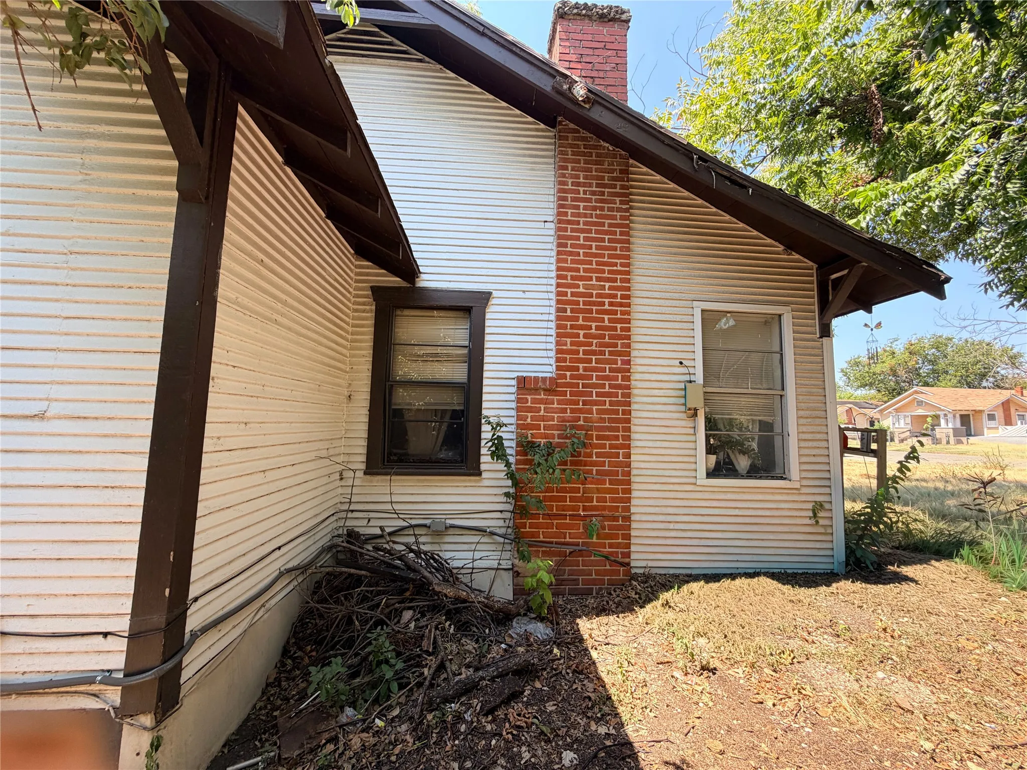Corrugated siding exterior with a brick chimney and brown trim