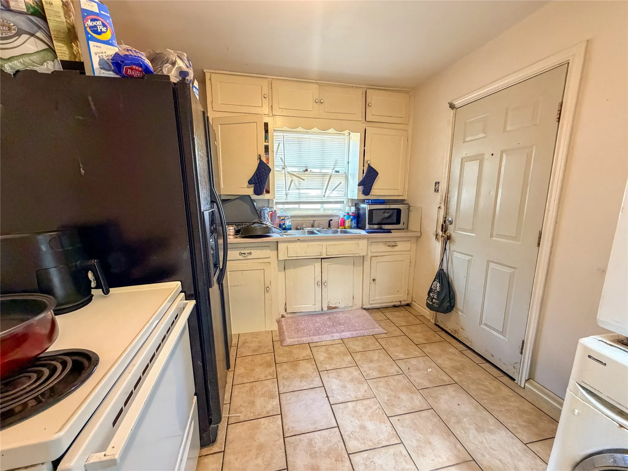 Kitchen featuring tile flooring, painted cabinetry, and a window above the sink