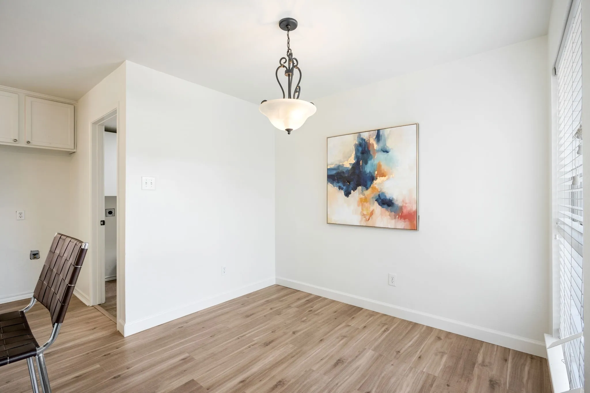 Wood-finish flooring, white walls, overhead light fixture, and window with blinds