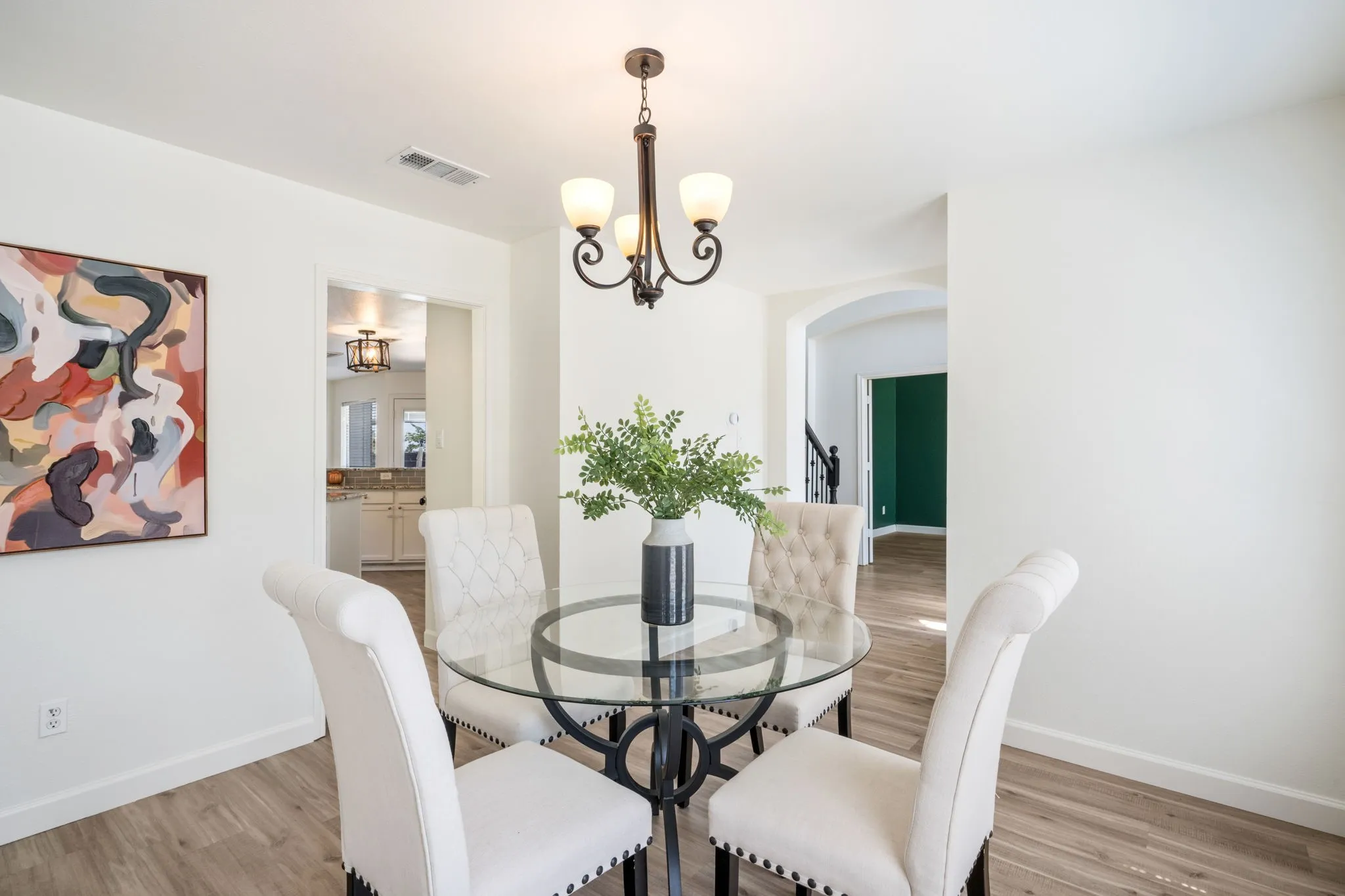 Wood-finish flooring with white walls and a bronze chandelier
