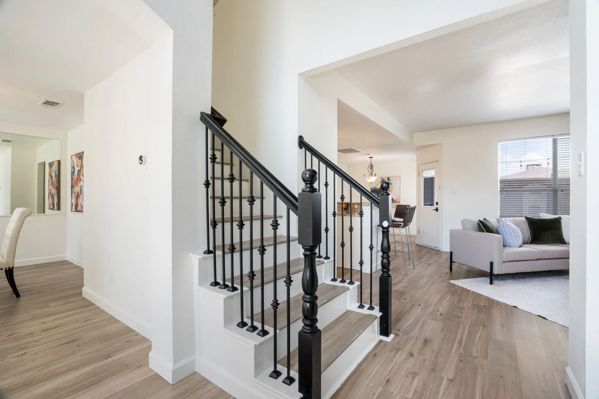 Staircase featuring black wrought iron balusters and wood-finish treads