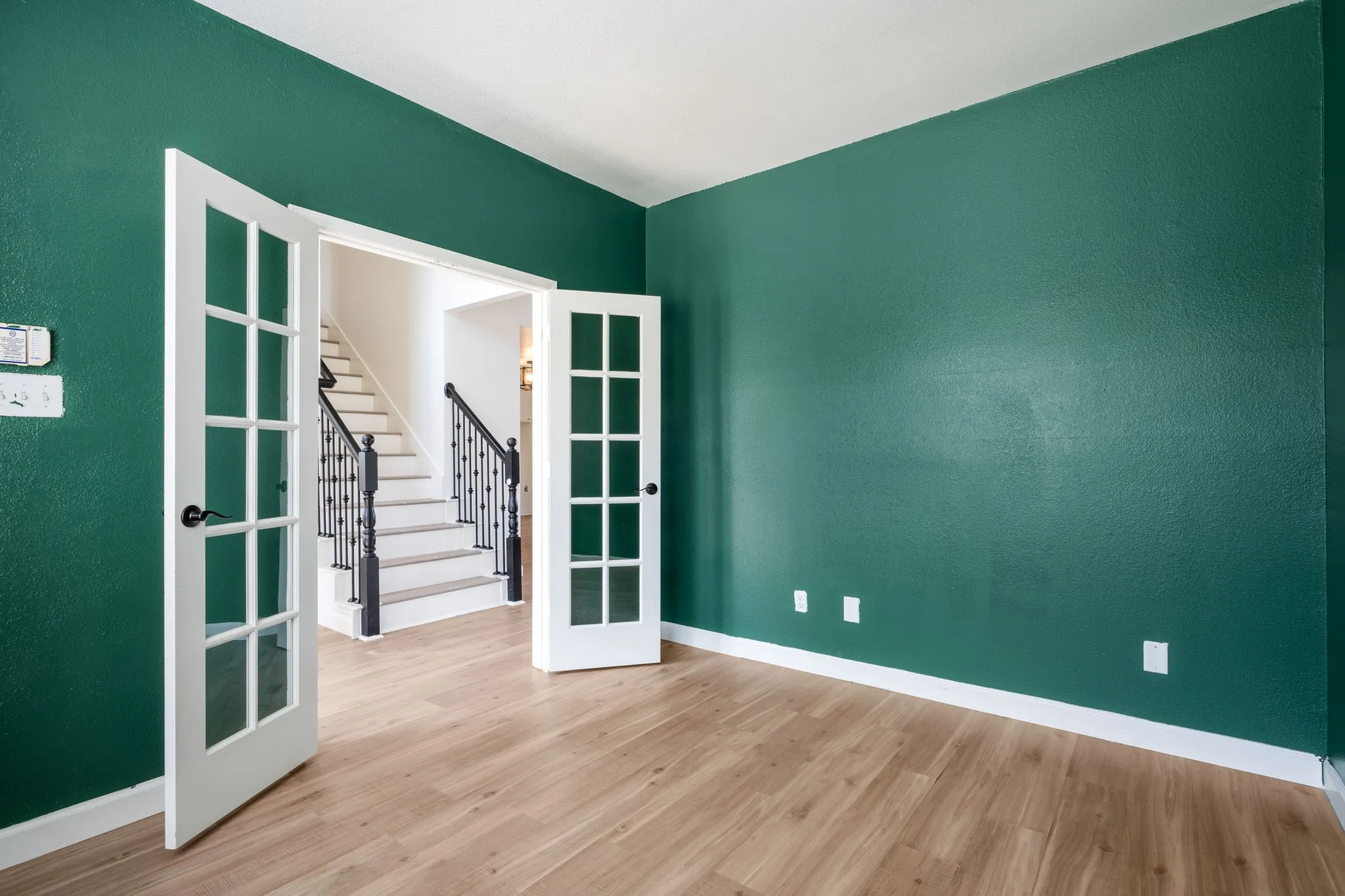 Wood-finish flooring with white trim, framed by a vibrant emerald wall color