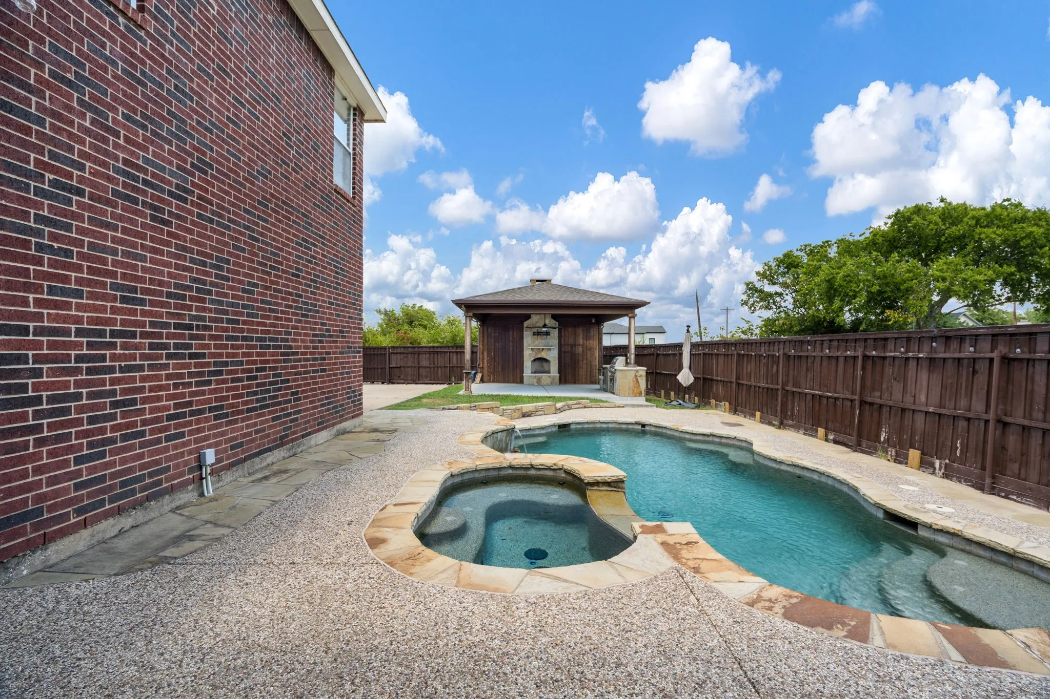 Saltwater pool & spa anchor the private outdoor oasis, surrounded by a stone-bordered deck, waterfall feature & overhead string lighting. The showpiece is a permanent timber-frame pergola, cedar-plank ceiling, wood-burning stone FP, built-in SS grill & outdoor refrigerator.