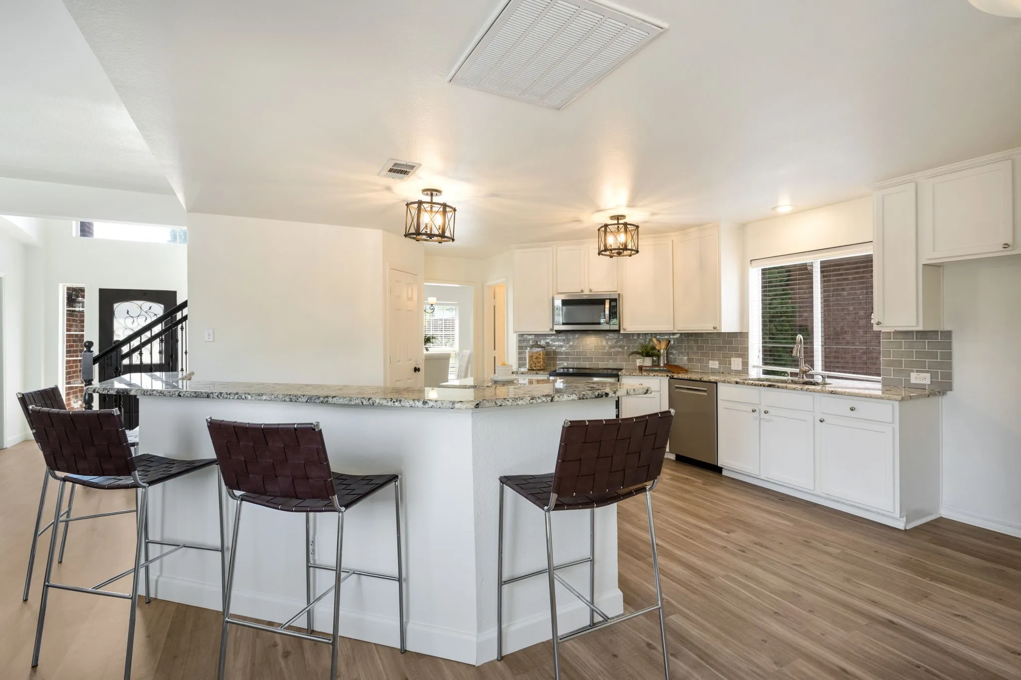 The kitchen has a professional induction range, dual ovens, built in air fryer, Bosch dishwasher, white shaker cabinets, granite counters and subway tile.