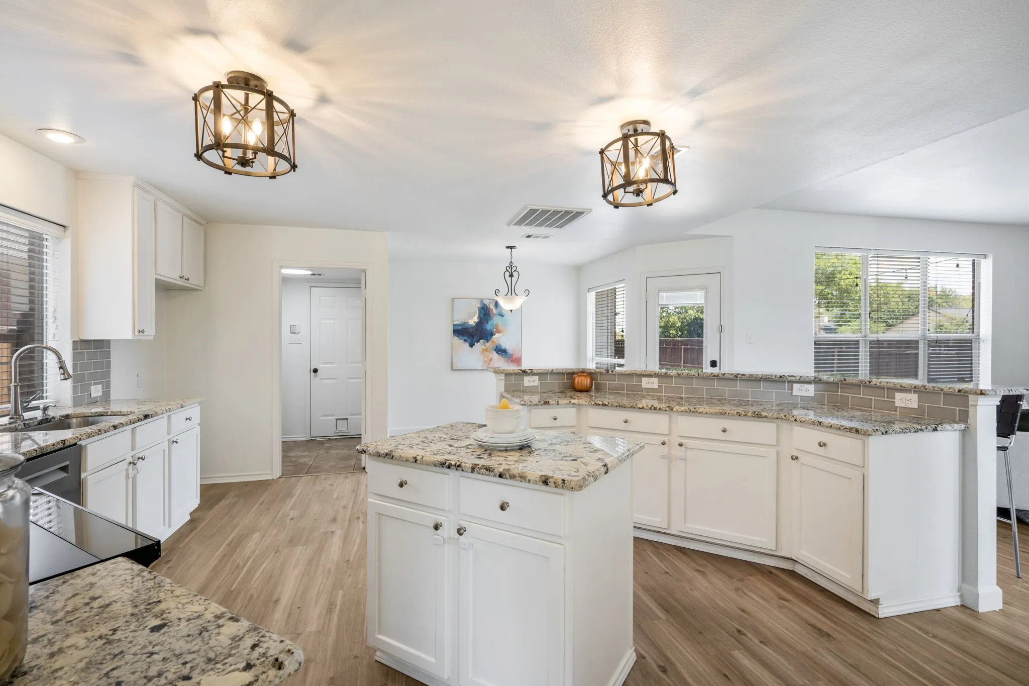 The kitchen has a professional induction range, dual ovens, built in air fryer, Bosch dishwasher, white shaker cabinets, granite counters and subway tile.