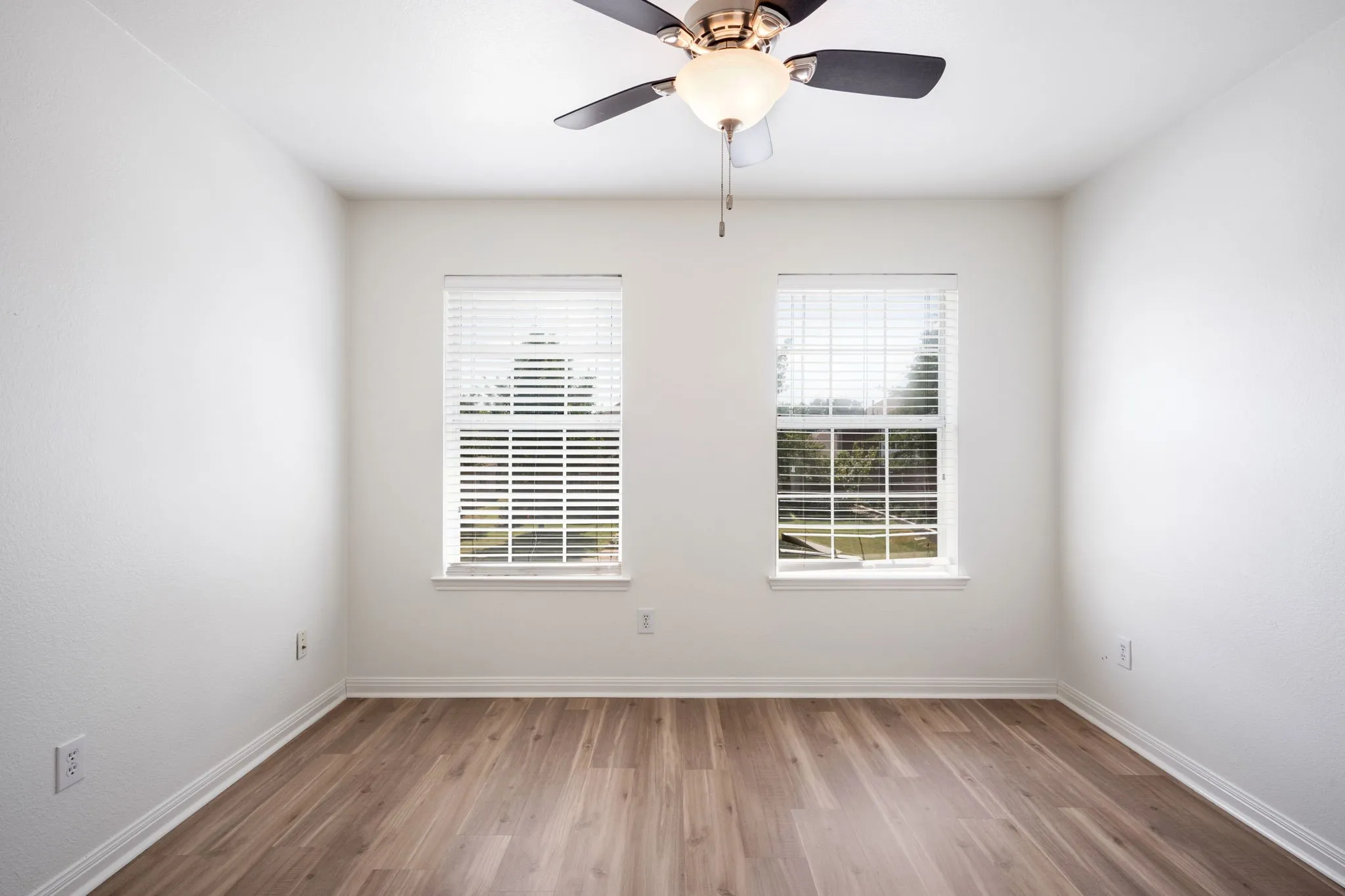 Living area featuring a fireplace with a stone surround, wood-finish flooring, and a ceiling fan