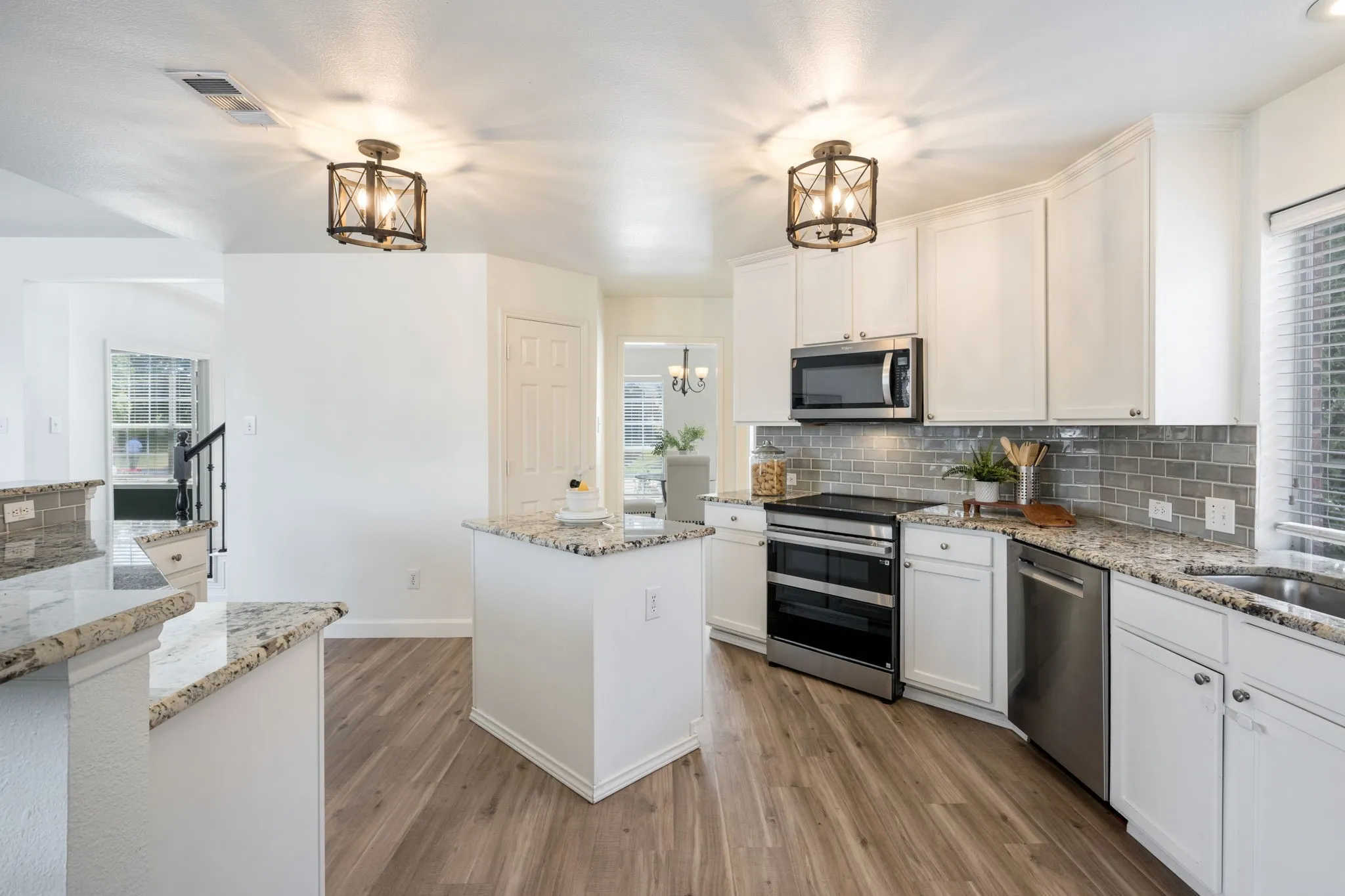 The kitchen has a professional induction range, dual ovens, built in air fryer, Bosch dishwasher, white shaker cabinets, granite counters and subway tile.