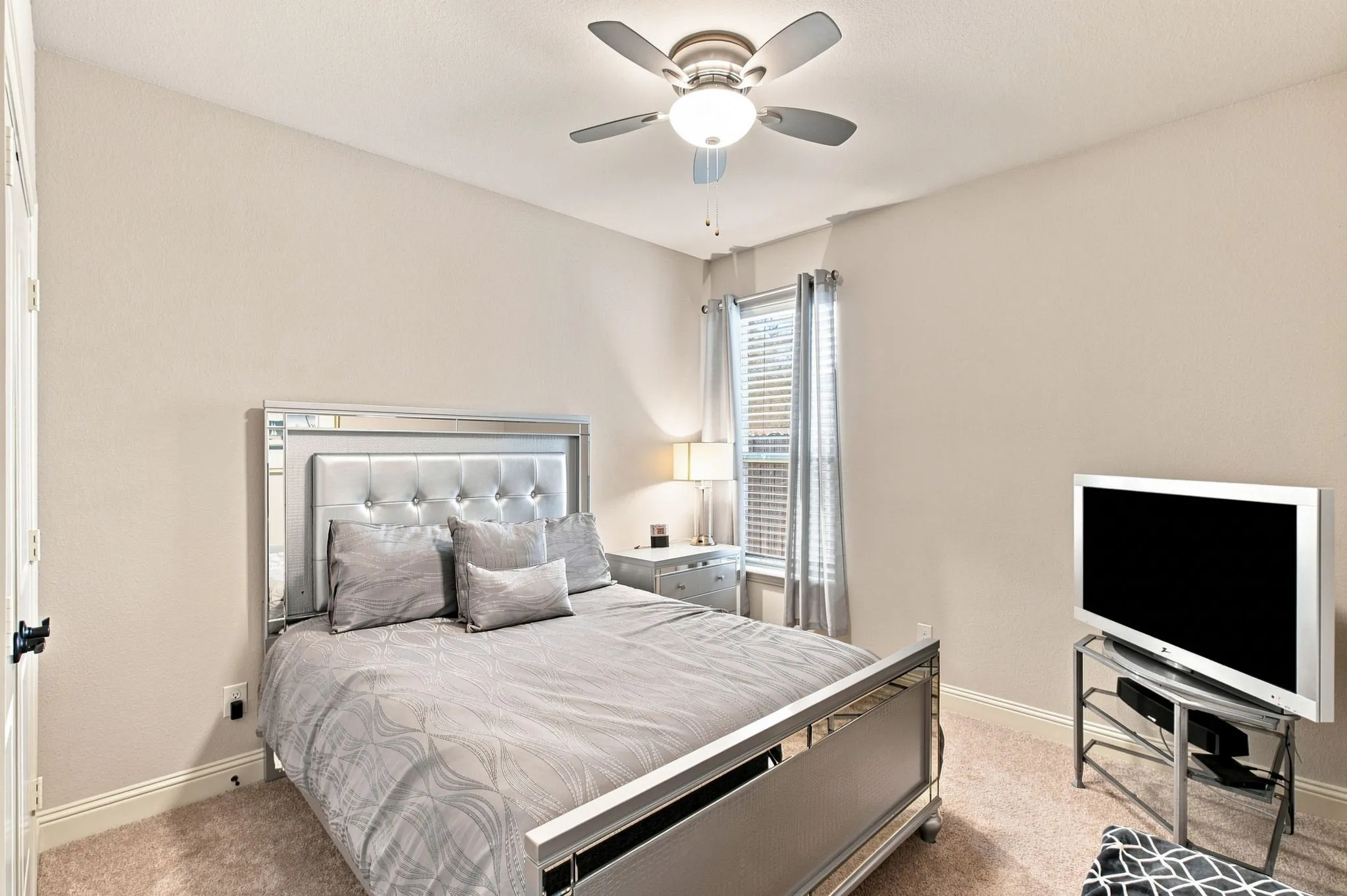 Recessed lighting and a ceiling fan are featured in this room with plush carpeting