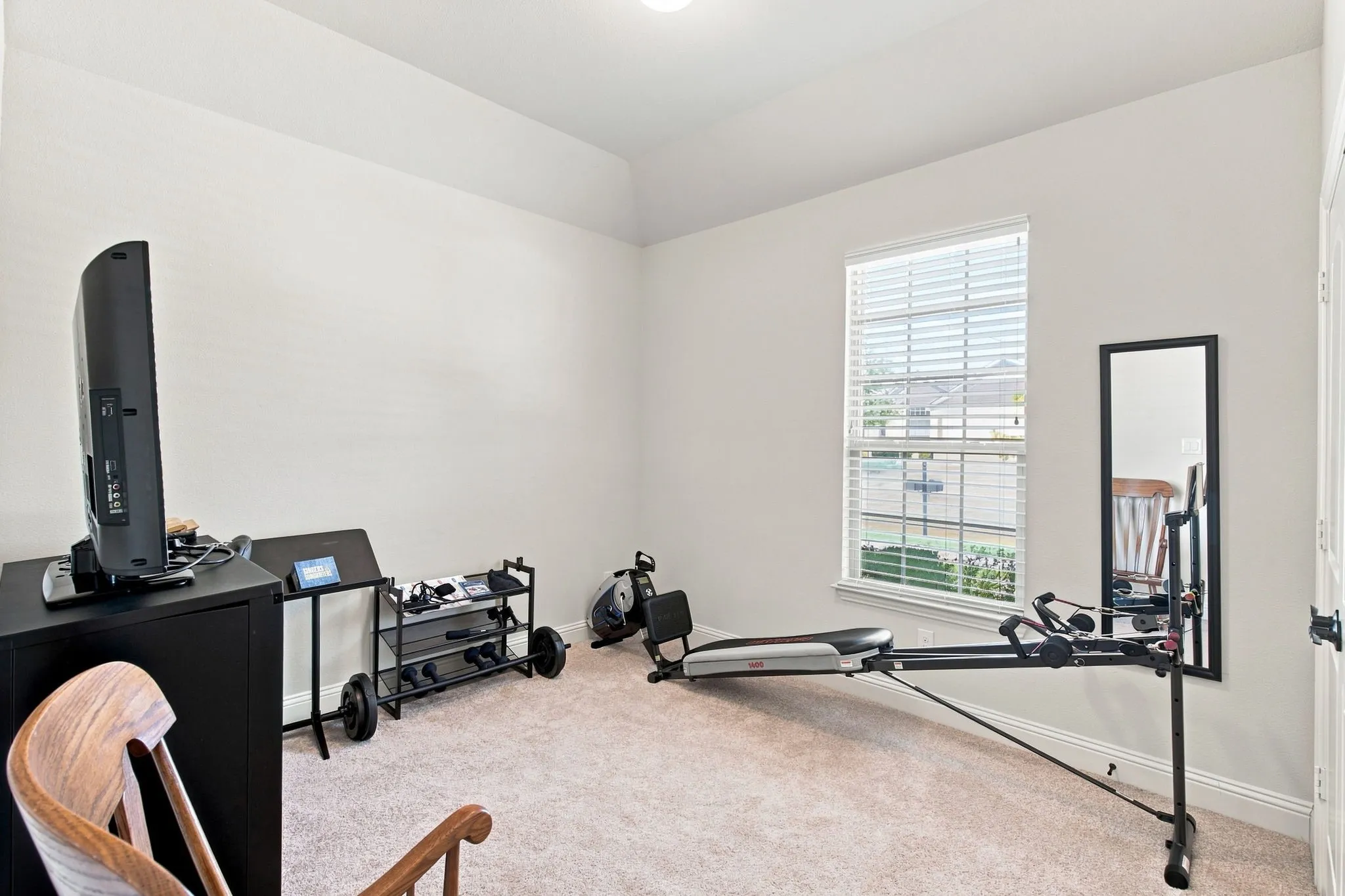 Tray ceiling with recessed lighting, single window with blinds, carpet flooring, and a white paneled door with black hardware