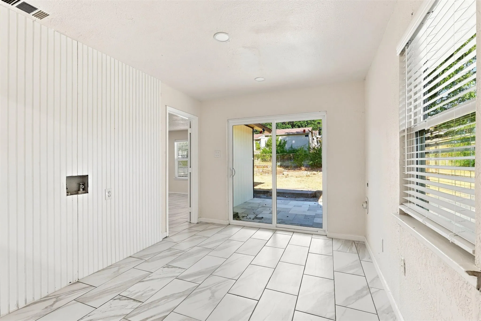 Sliding glass door, recessed lighting, tile flooring, vertical slat wall paneling