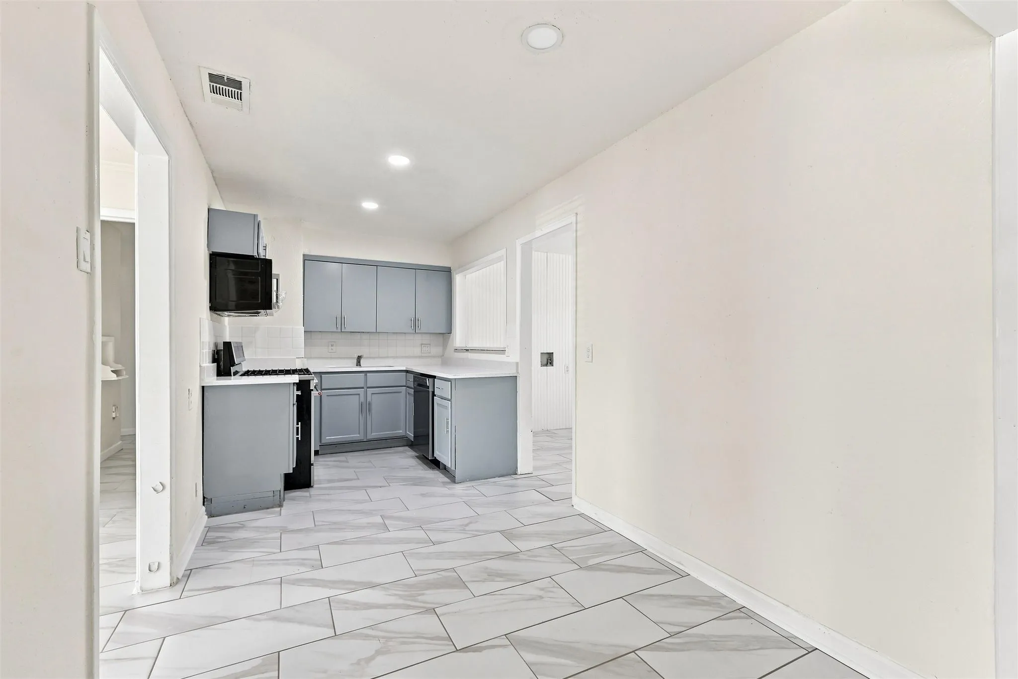 Kitchen featuring gray cabinetry, white countertops, built-in microwave, and tile flooring