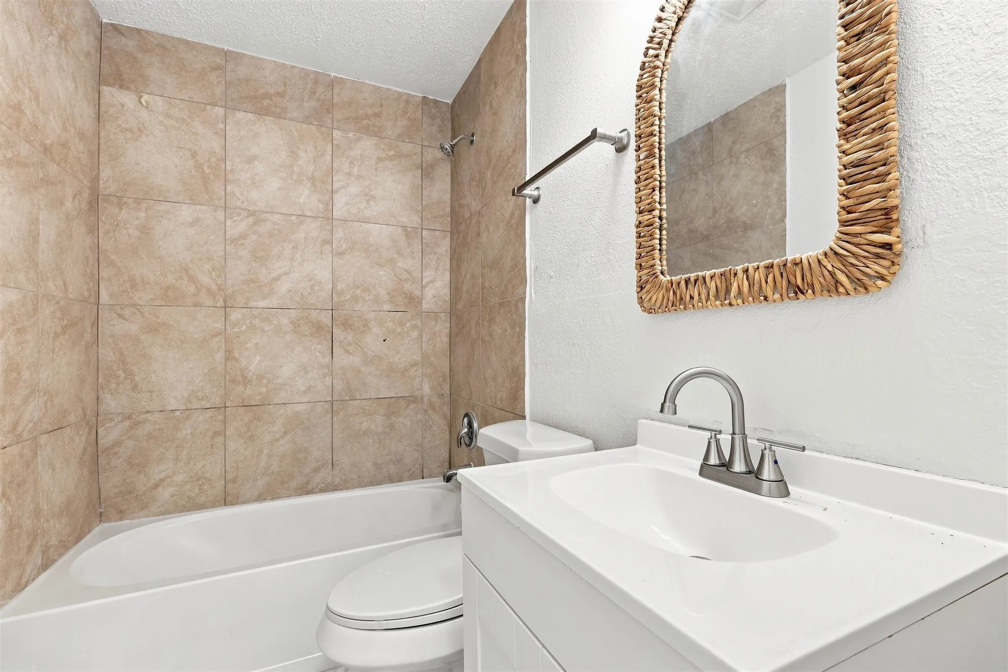 White vanity with an integrated sink, brushed nickel faucet, and a wall-mounted mirror