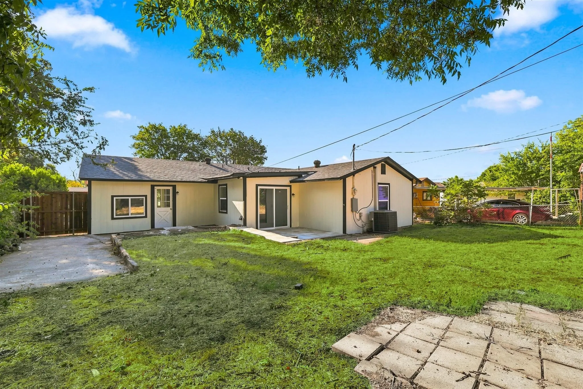 Expansive backyard with a manicured lawn, concrete patio, and a privacy fence