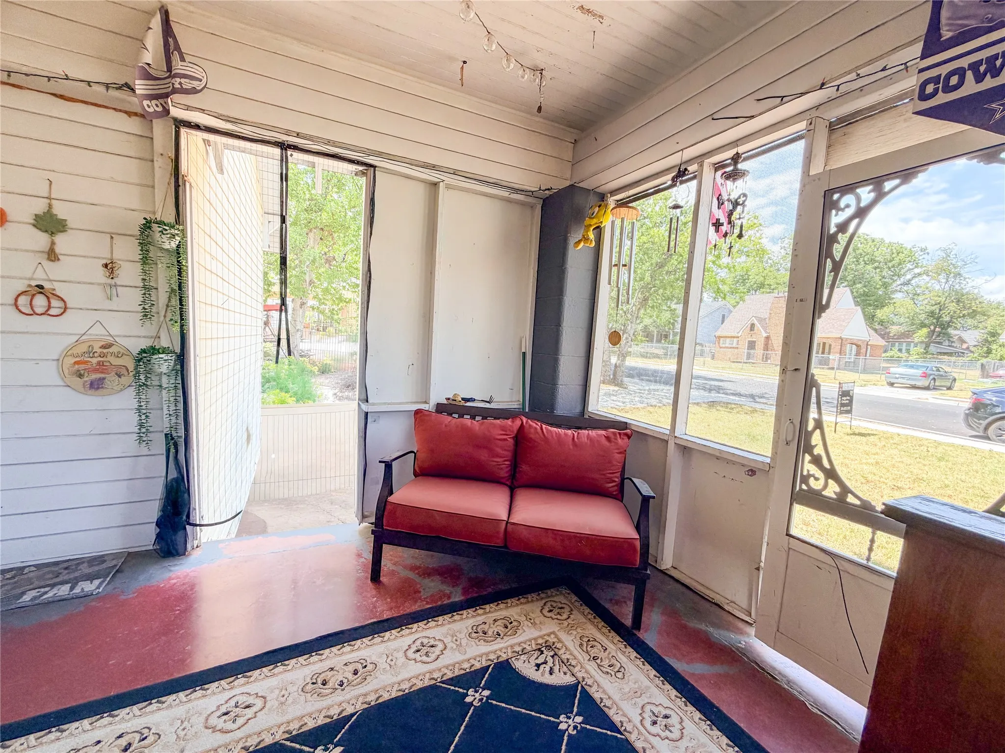 Screened porch with painted concrete flooring and white paneled walls