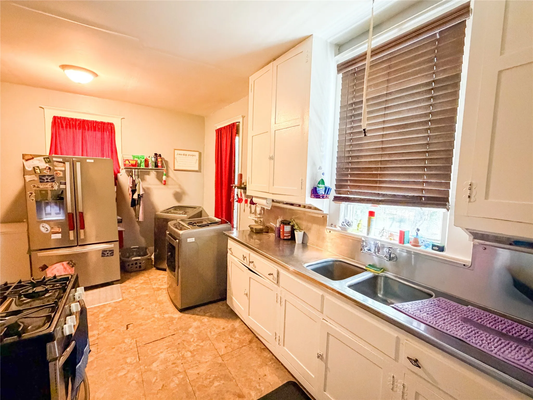 White cabinetry, stainless steel countertops, and a double basin sink