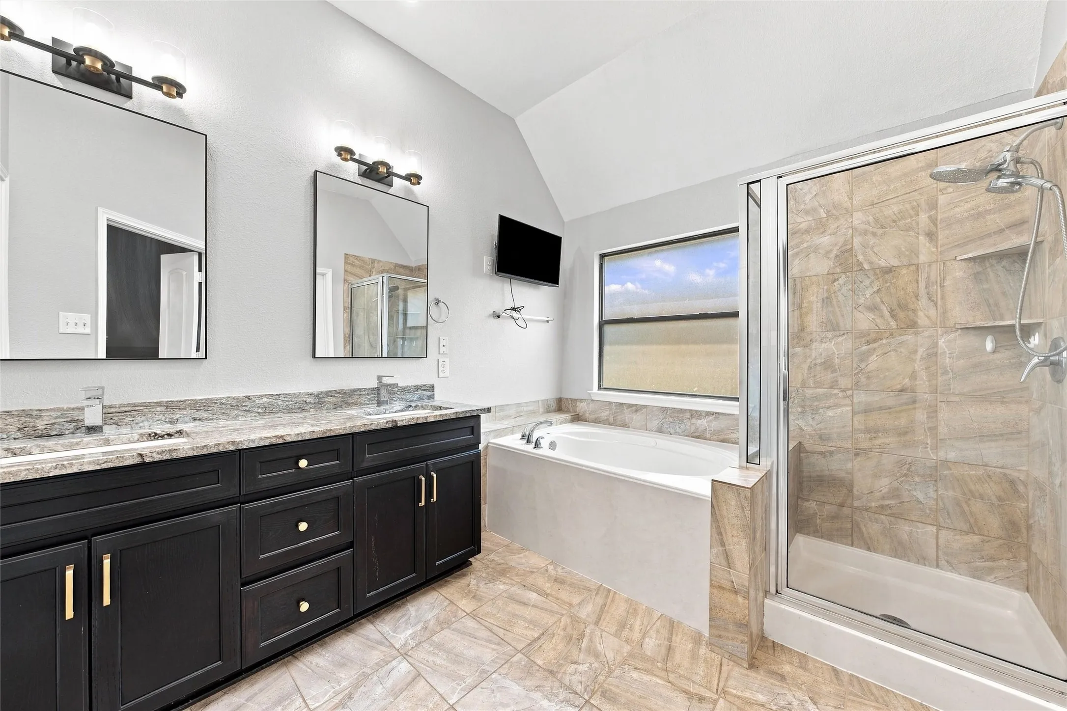 Spa-inspired primary bathroom featuring a dual-sink vanity with black cabinetry, quartz countertop with mosaic tile backsplash, and polished nickel hardware