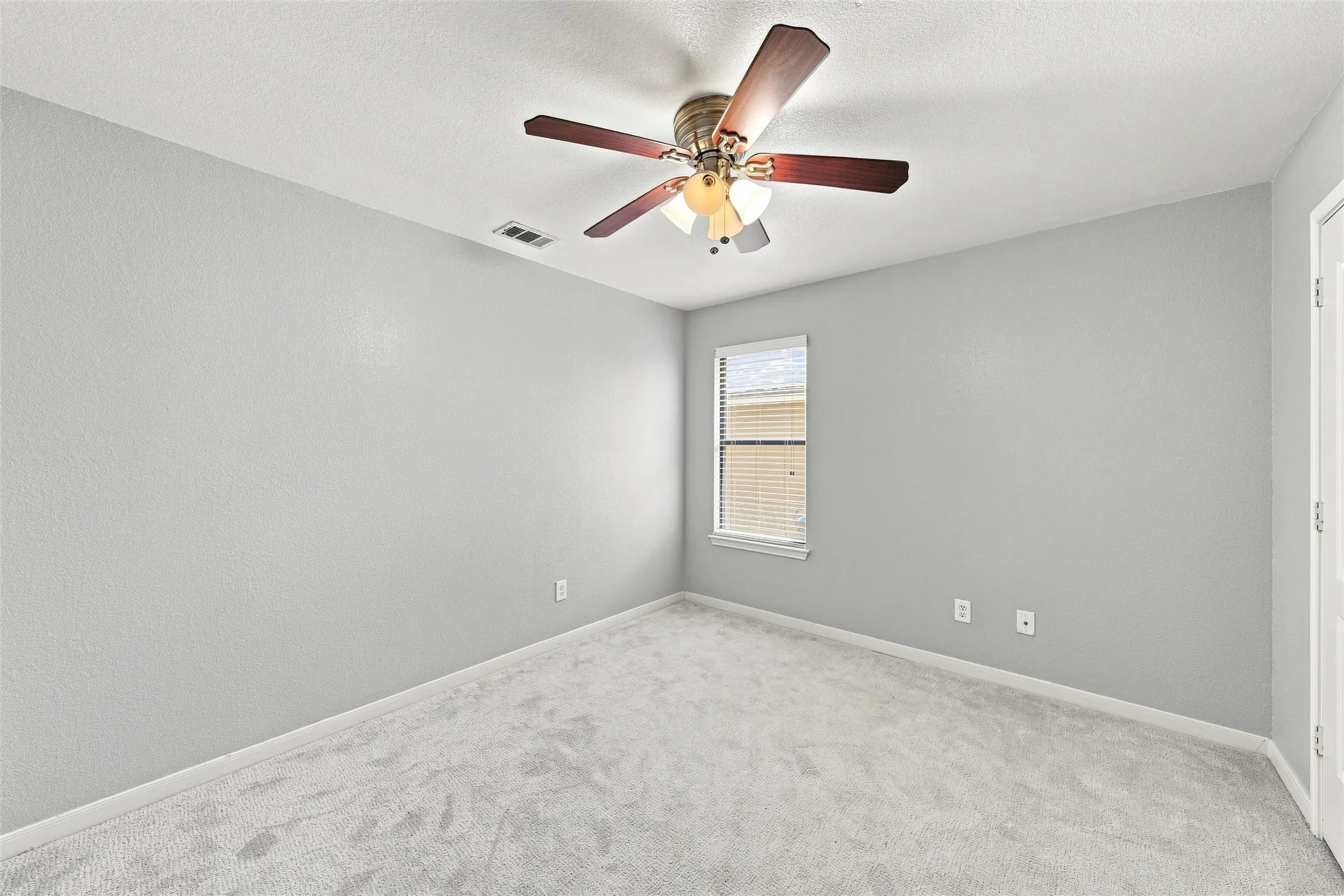 Another comfortable bedroom with soft carpet and natural light.