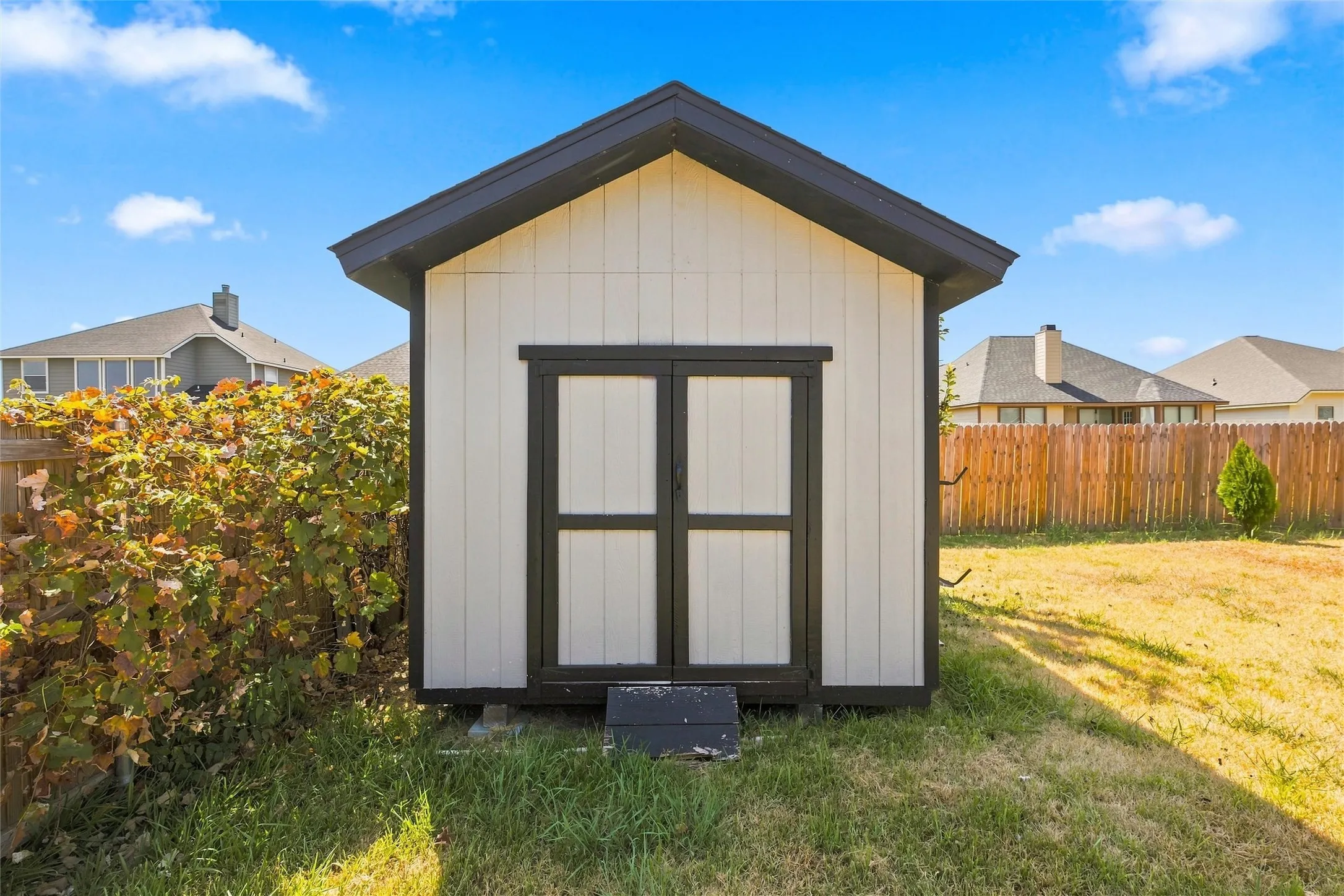 Detached storage shed featuring board and batten siding, black trim, and a gabled roof