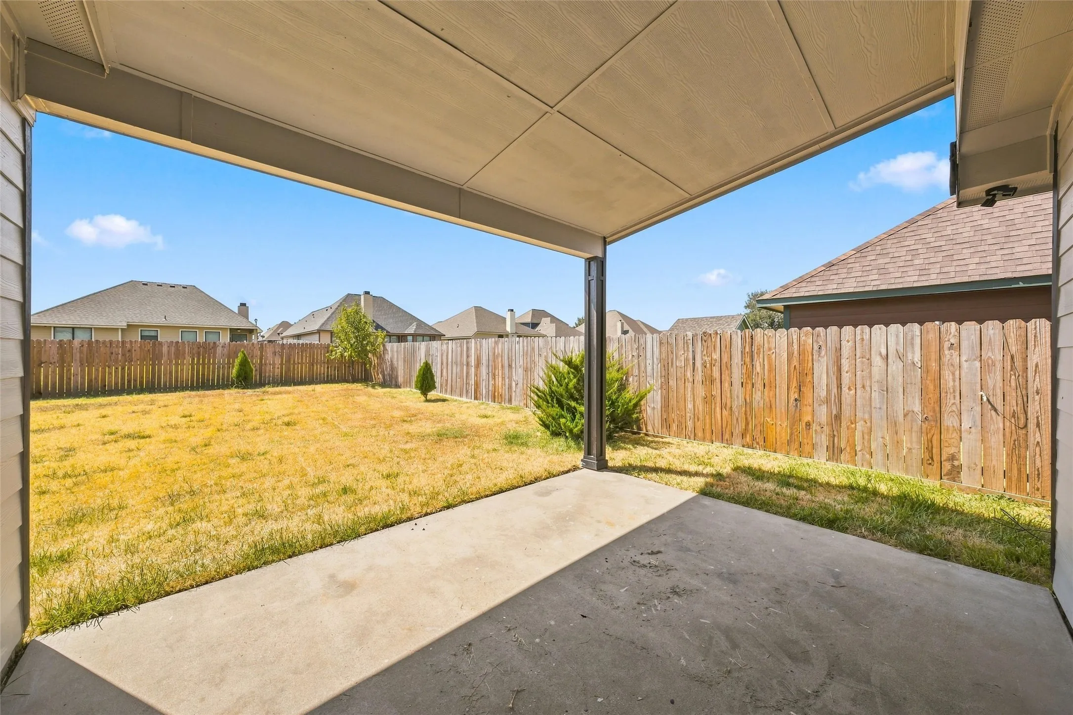 Covered patio with a concrete surface, a wood privacy fence, and an expansive lawn
