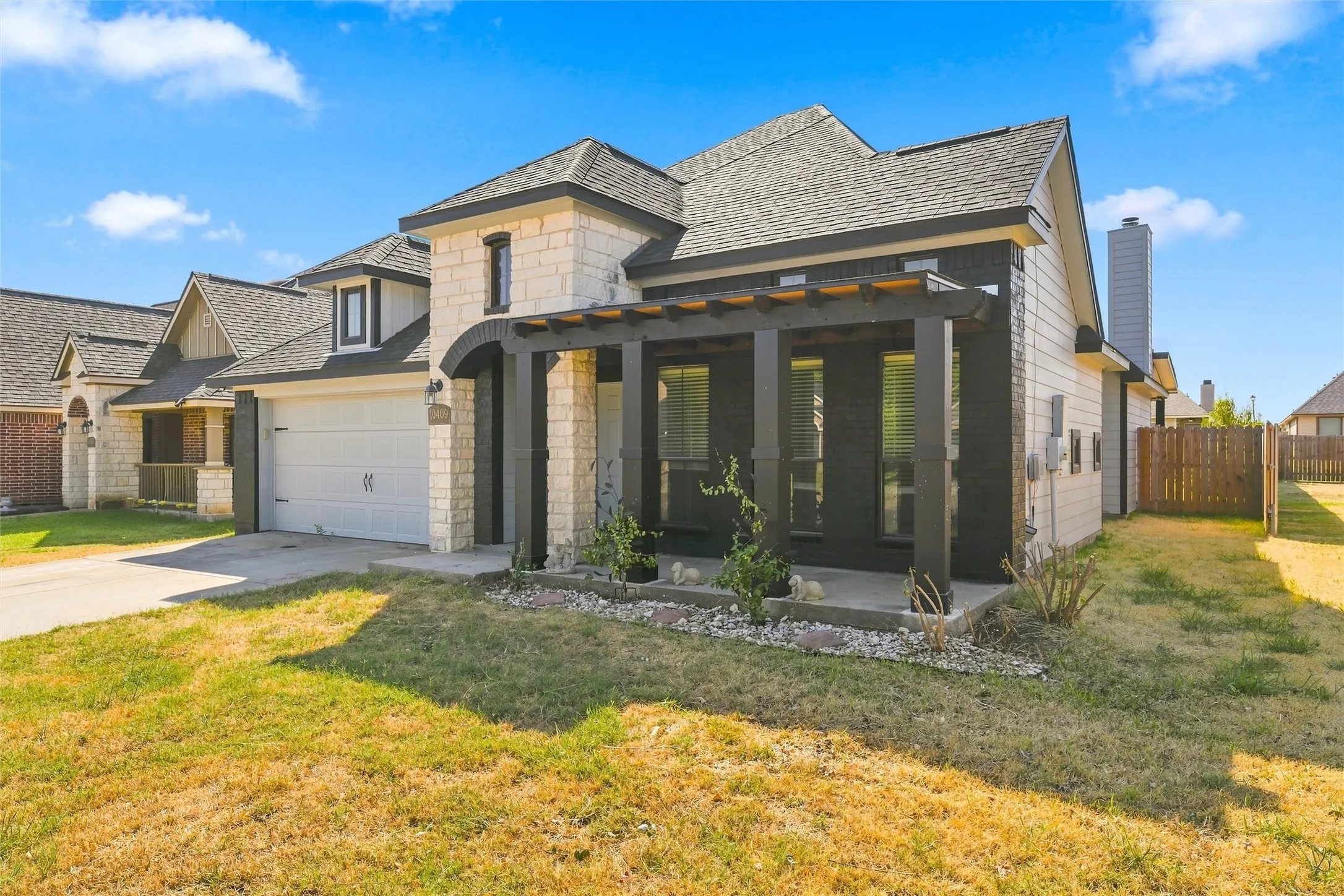 Modern two-story residence featuring a striking stone and composite exterior, gabled roofline with architectural detailing, and a welcoming front entry with dark-framed glass doors and sidelights