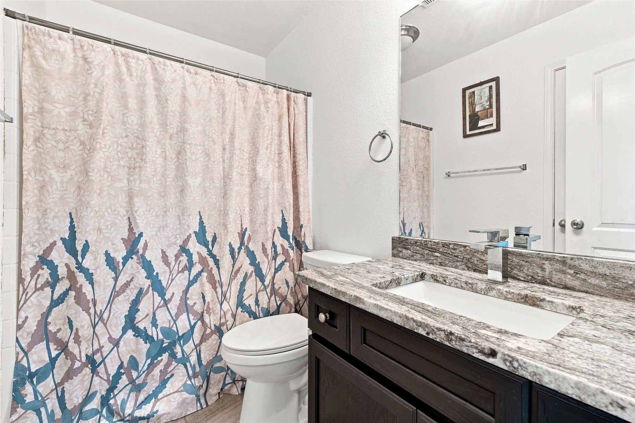 Vanity with a rectangular undermount sink, stone countertop, and chrome faucet