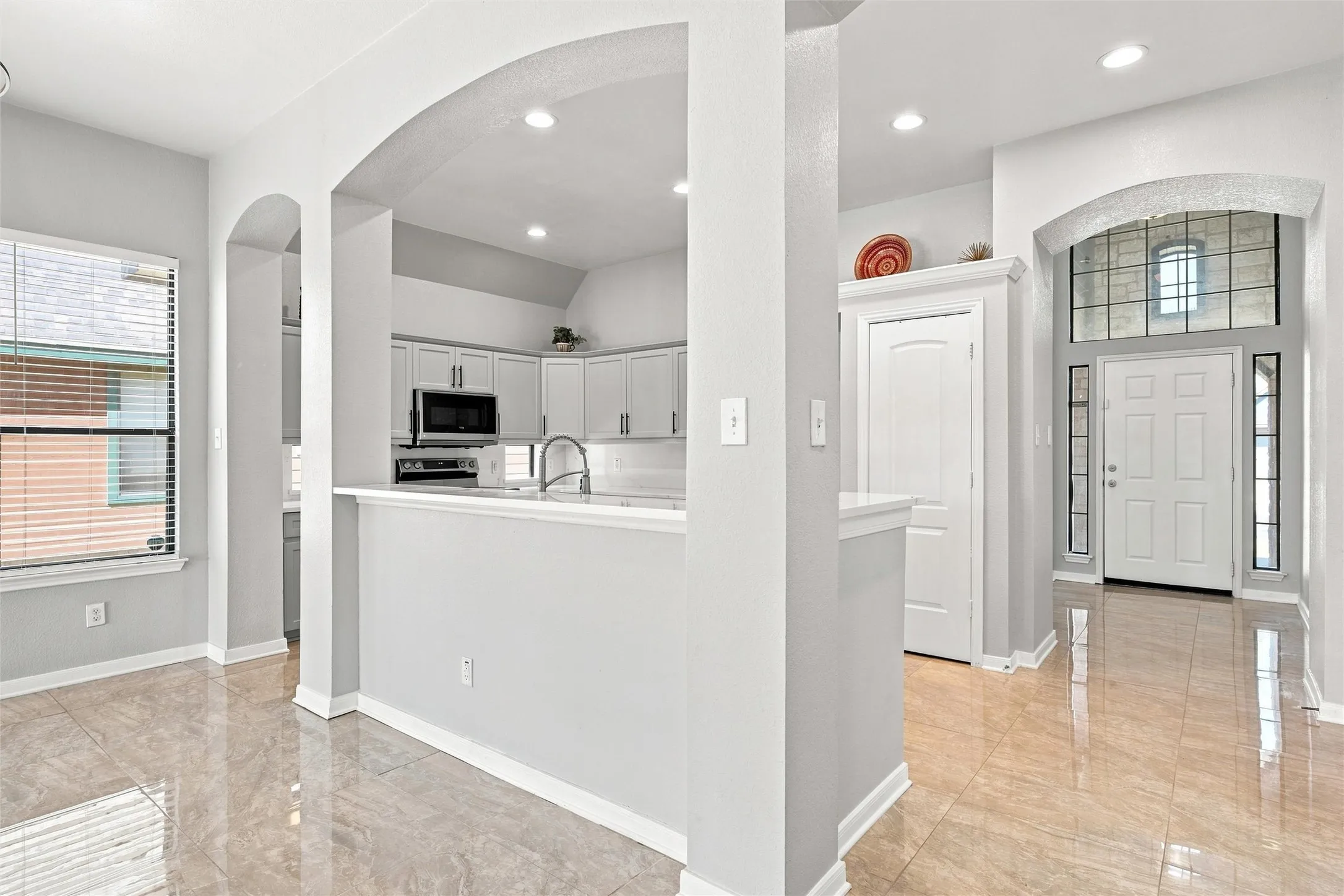 Clean-lined cabinetry, stainless appliances, and a peninsula counter create a functional layout with sightlines into the main living area.