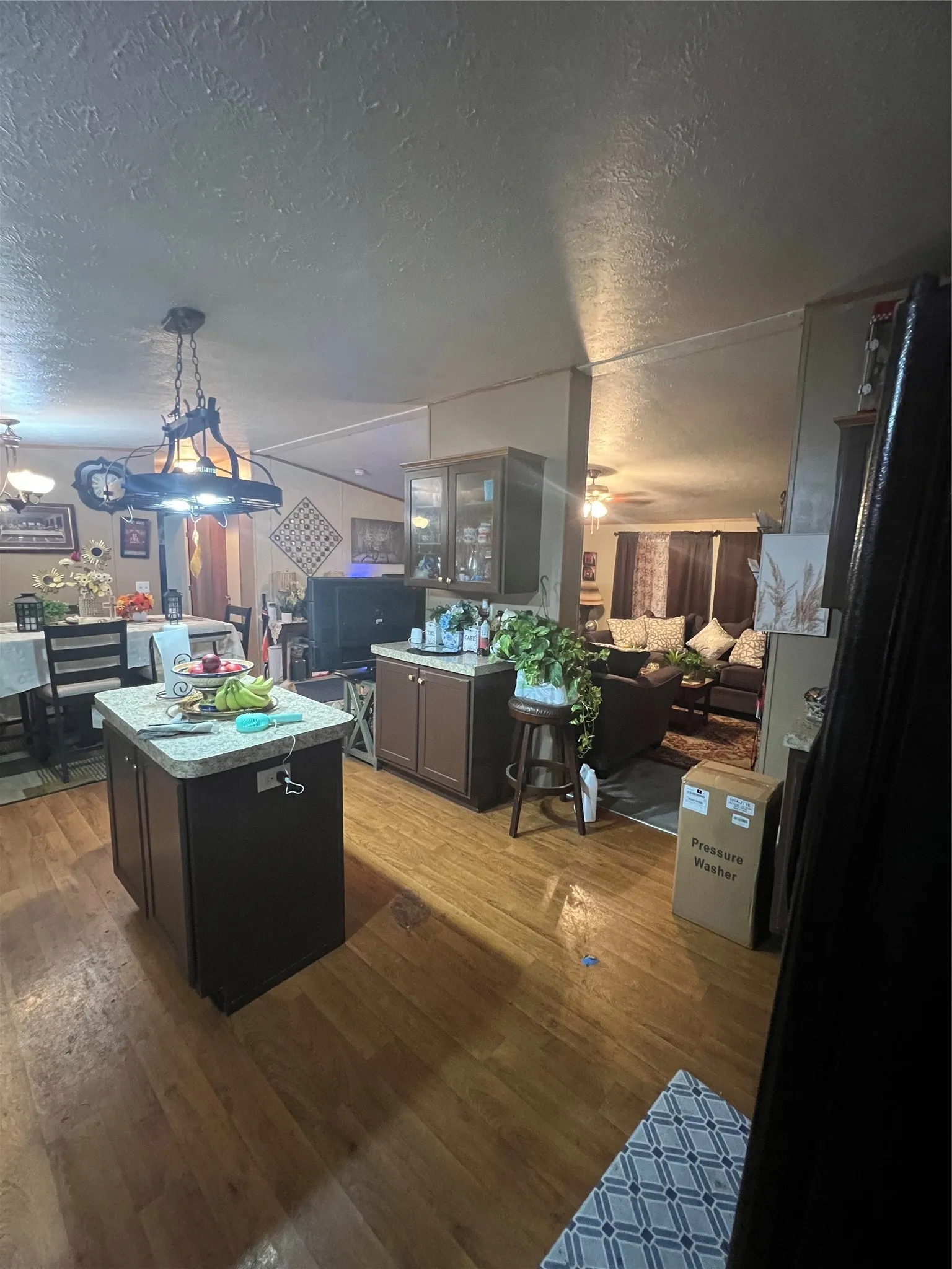 Wood-finish flooring throughout, kitchen island with countertop, built-in cabinetry with glass doors, and recessed lighting