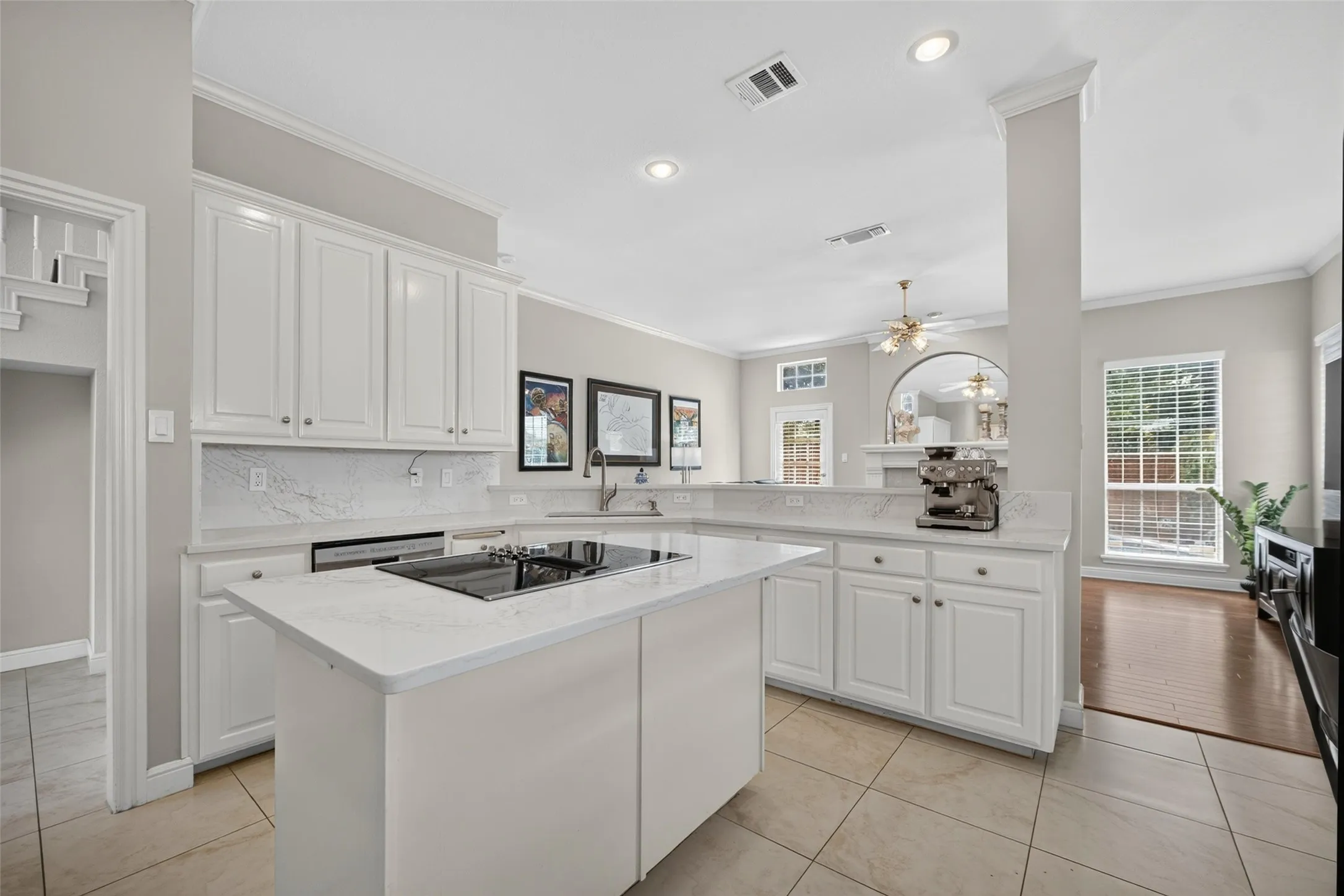 Kitchen featuring an integrated cooktop, white cabinetry, a central island, recessed lighting, and tile flooring