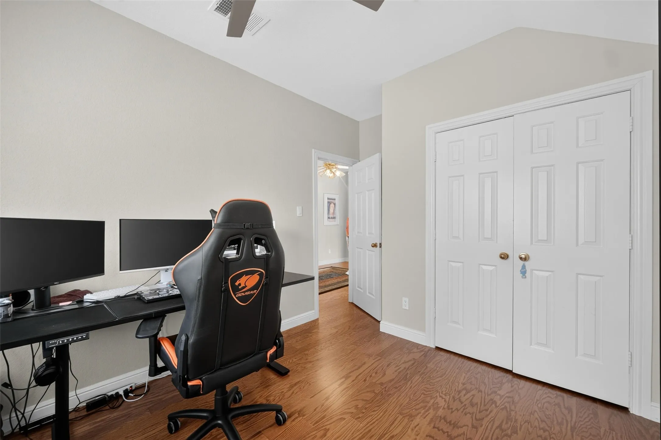 Wood-finish flooring, white paneled bifold closet doors, and a ceiling fan with integrated lighting