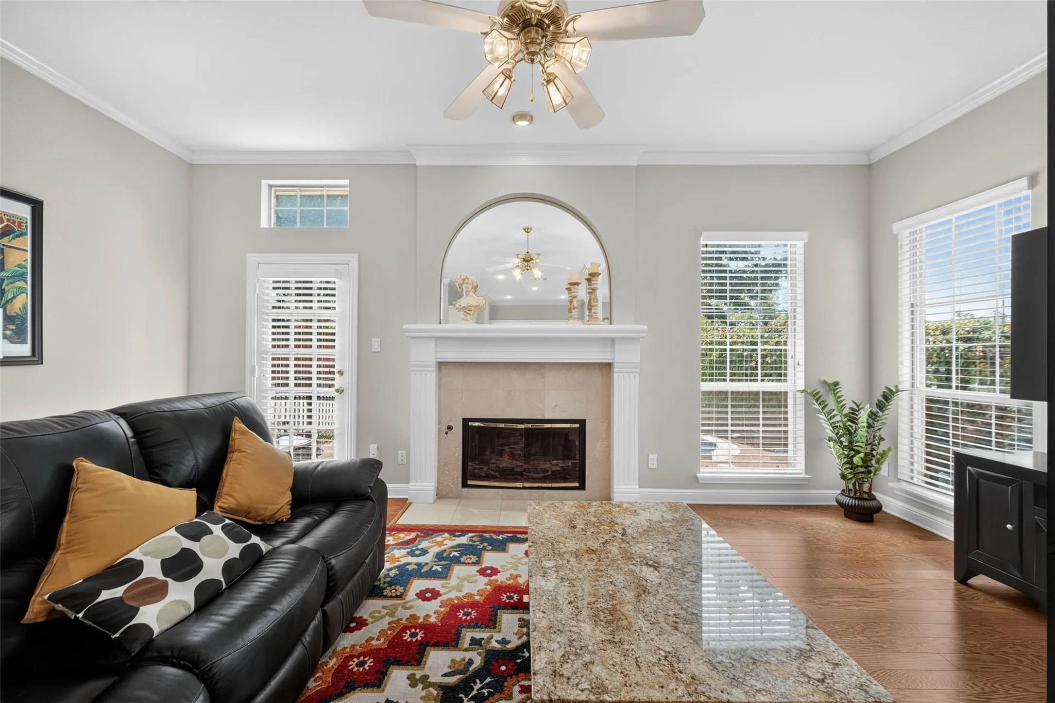 Wood-finish flooring, crown molding, and a ceiling fan with light fixture
