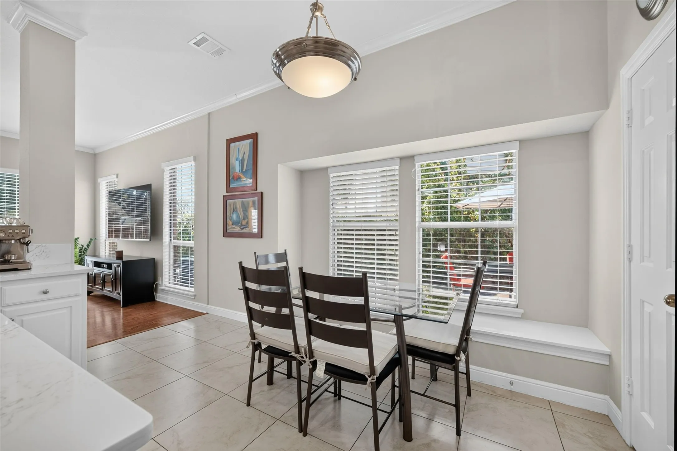 Recessed window seating, tile flooring, pendant lighting, crown molding, and white cabinetry