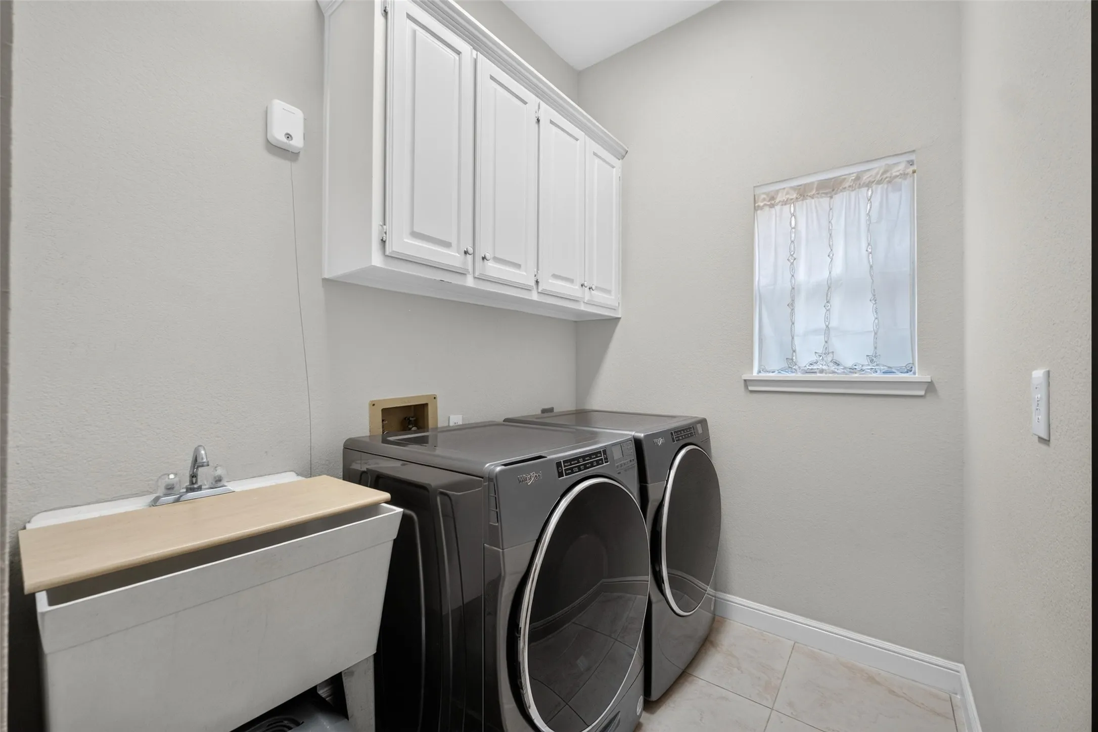 Built-in cabinetry, utility sink with faucet, and tile flooring