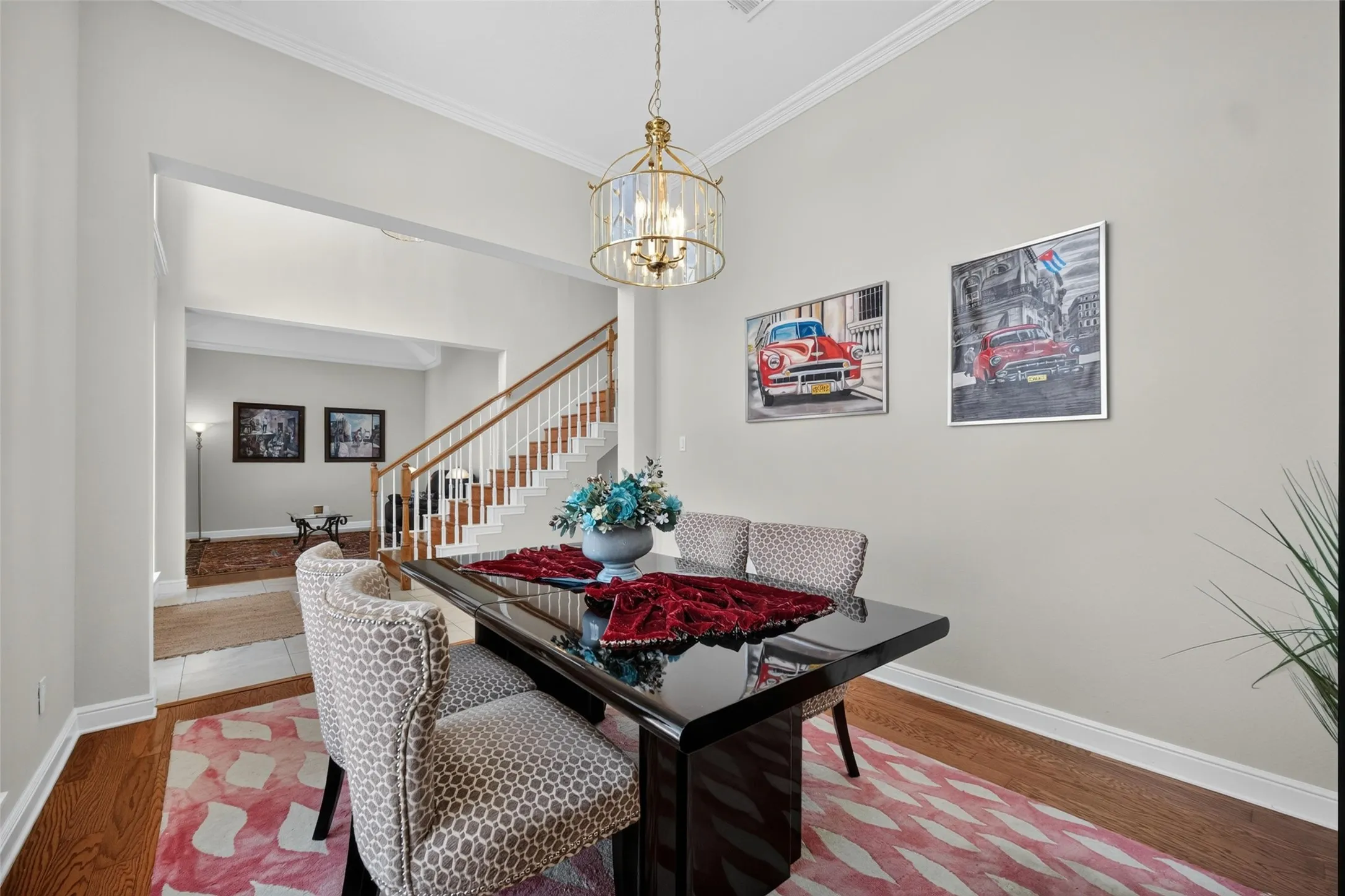 Hardwood flooring, crown molding, and a chandelier with a metal and glass frame