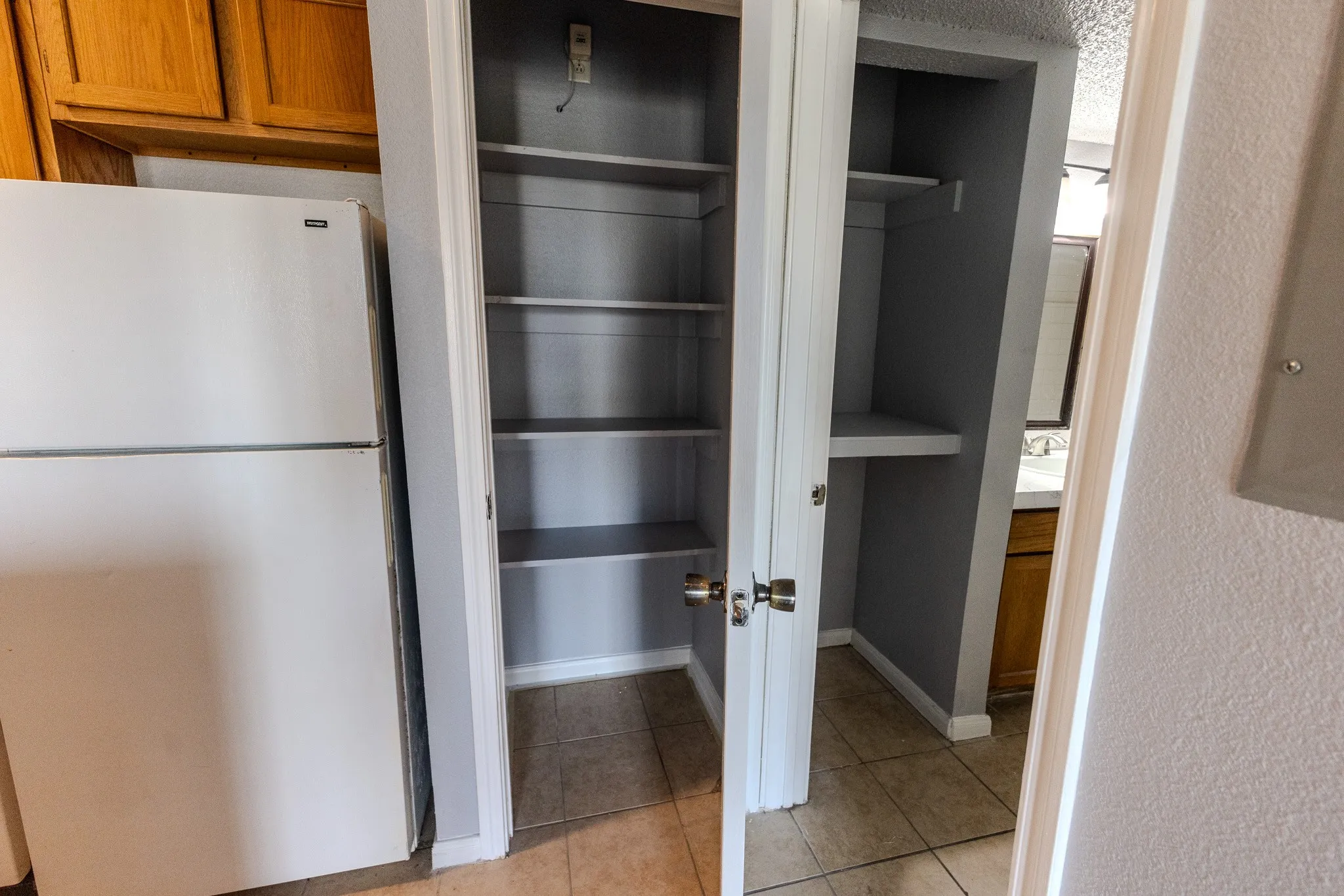 Built-in shelving, tile flooring, white bi-fold doors, wood cabinetry