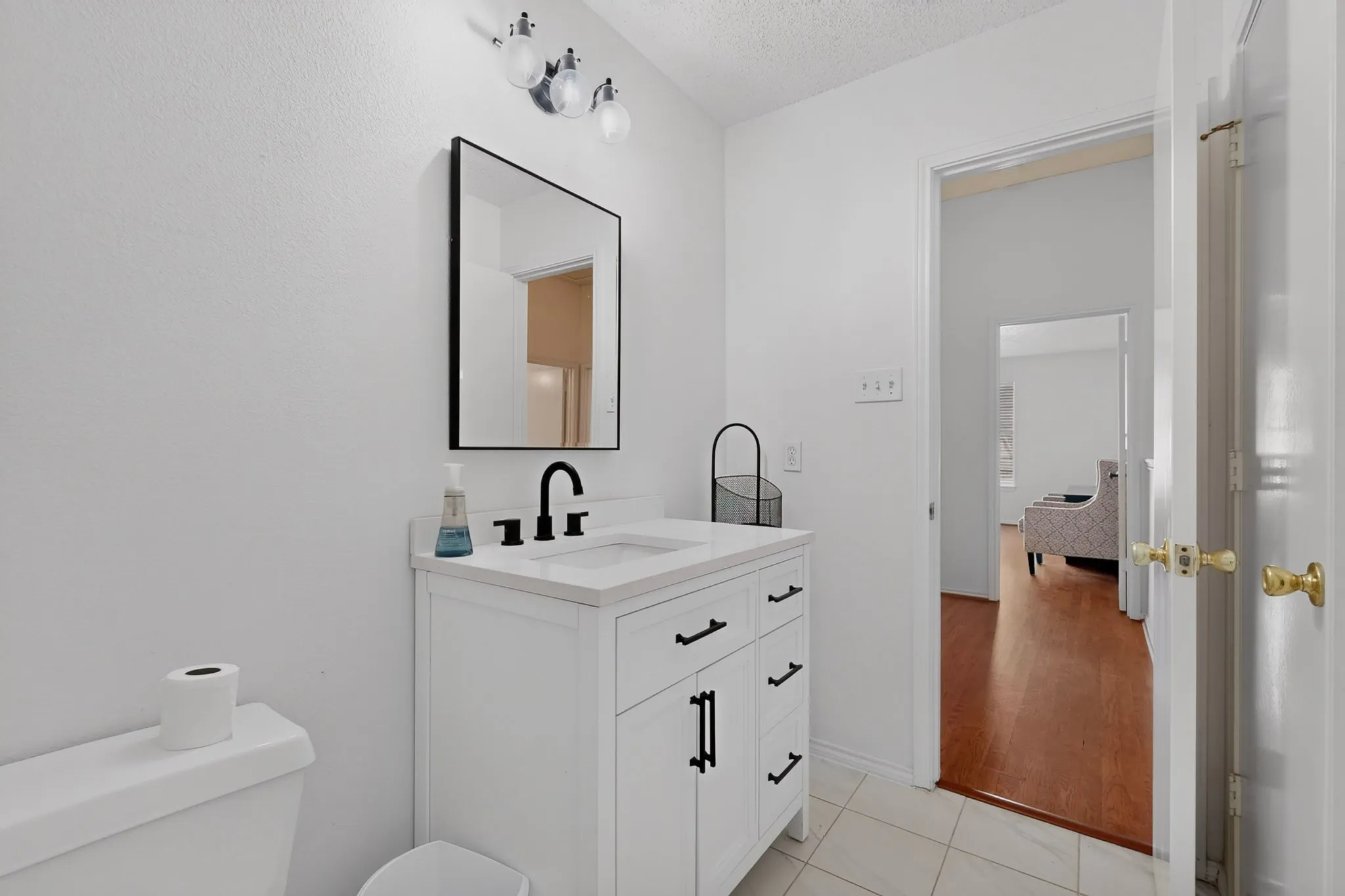 White vanity with a single basin, black hardware, black faucet, and a black-framed mirror
