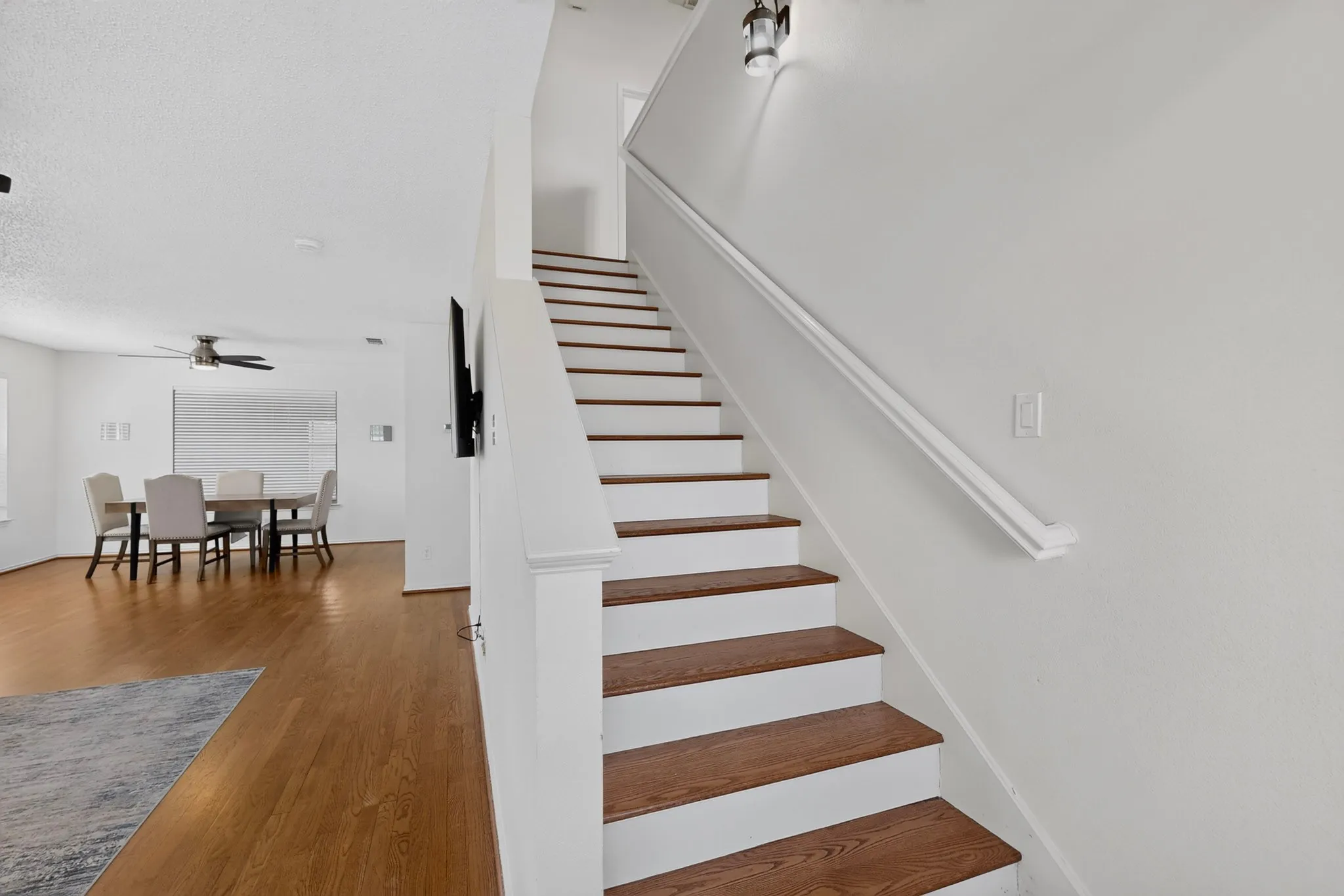 Staircase with wood-finish treads and white risers, featuring a white handrail
