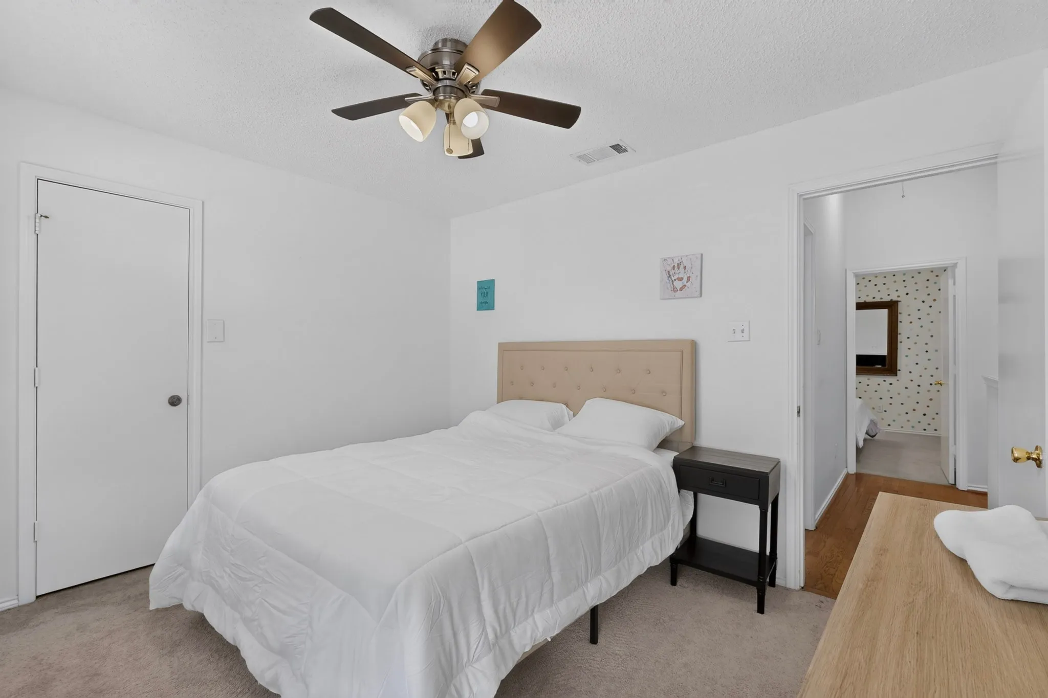Textured carpet flooring, ceiling fan with integrated lighting, door with satin nickel hardware, neutral wall paint