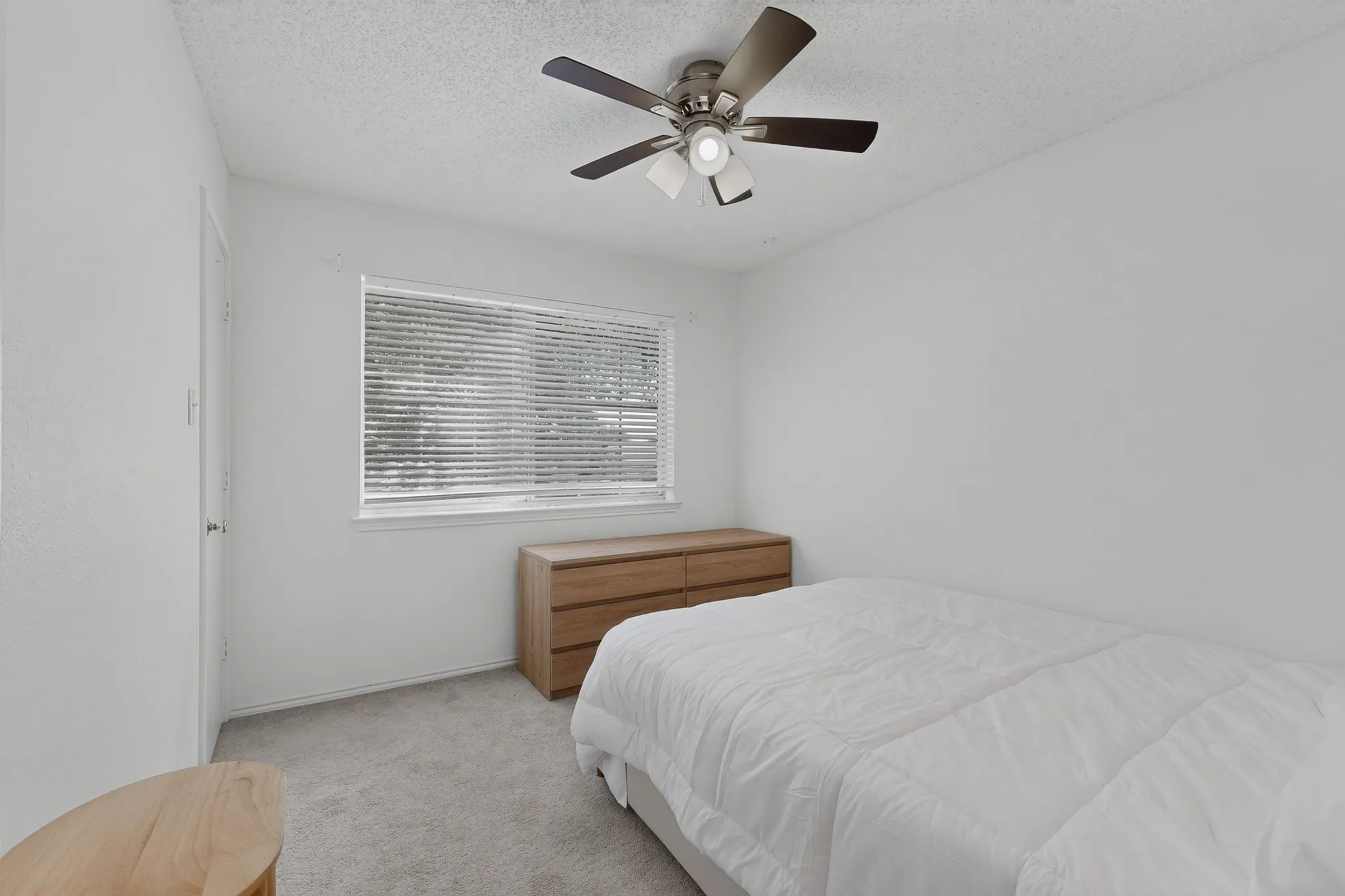 Recessed window with blinds, ceiling fan with integrated lighting, and neutral carpeting