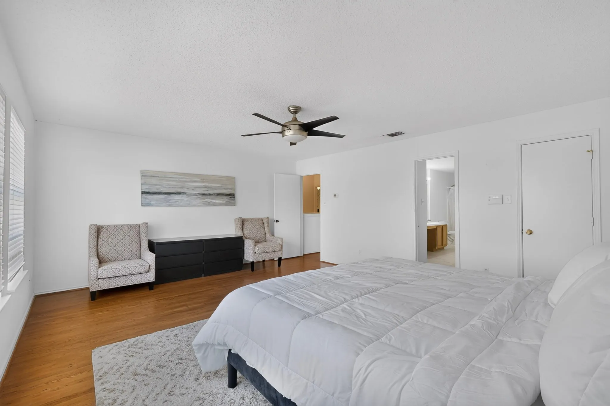 Wood-finish flooring with a ceiling fan and white interior walls