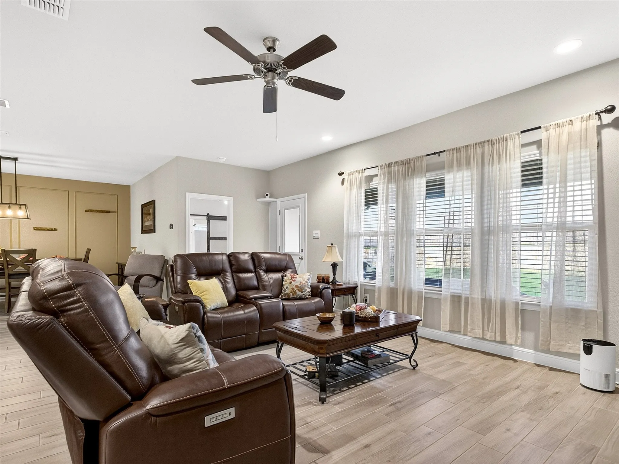 Recessed lighting, wood-finish flooring, ceiling fan, multiple windows with blinds, and decorative wall paneling