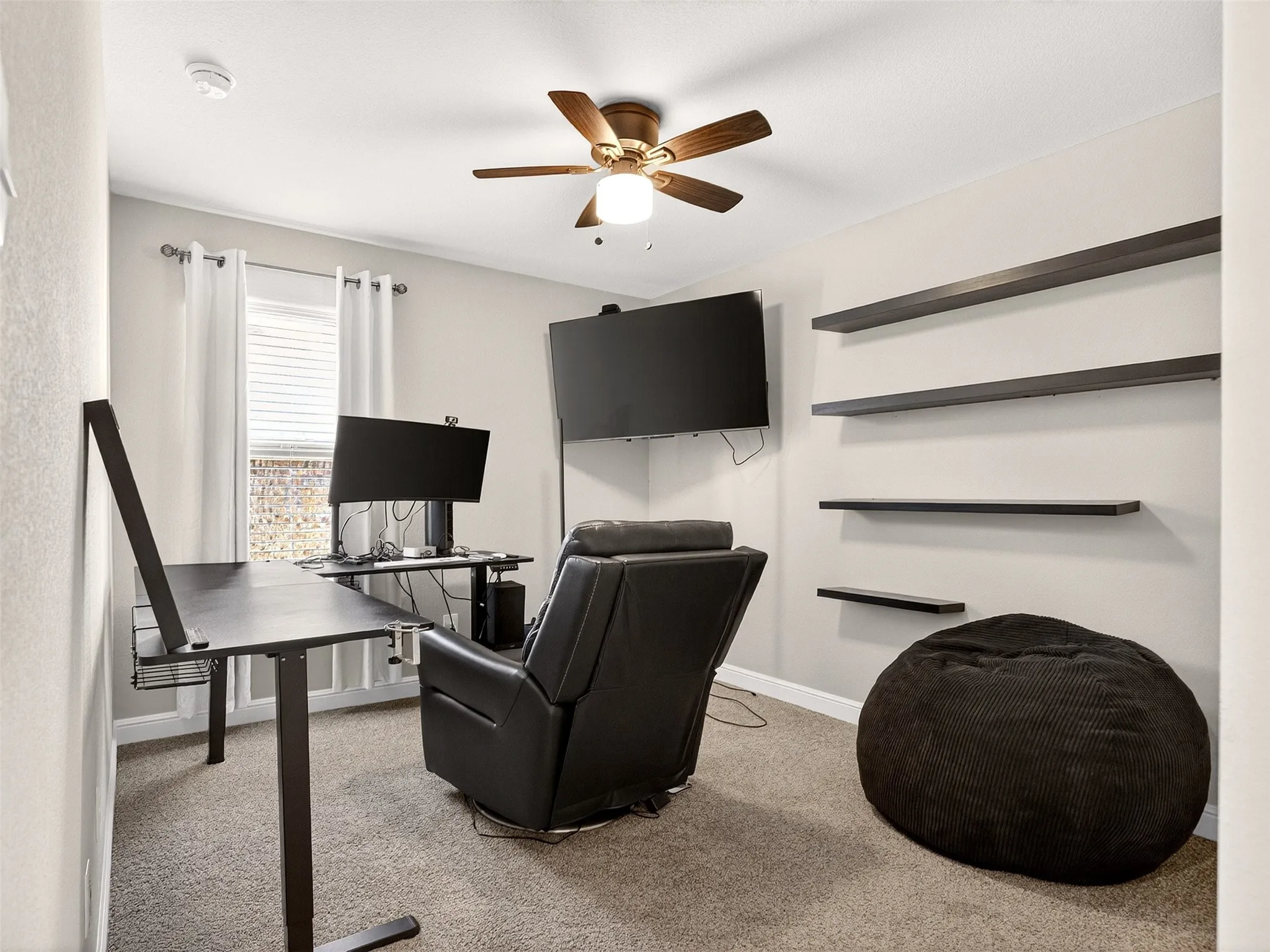 Recessed lighting, ceiling fan with light fixture, window with blinds, wall-mounted shelving, and carpeted flooring