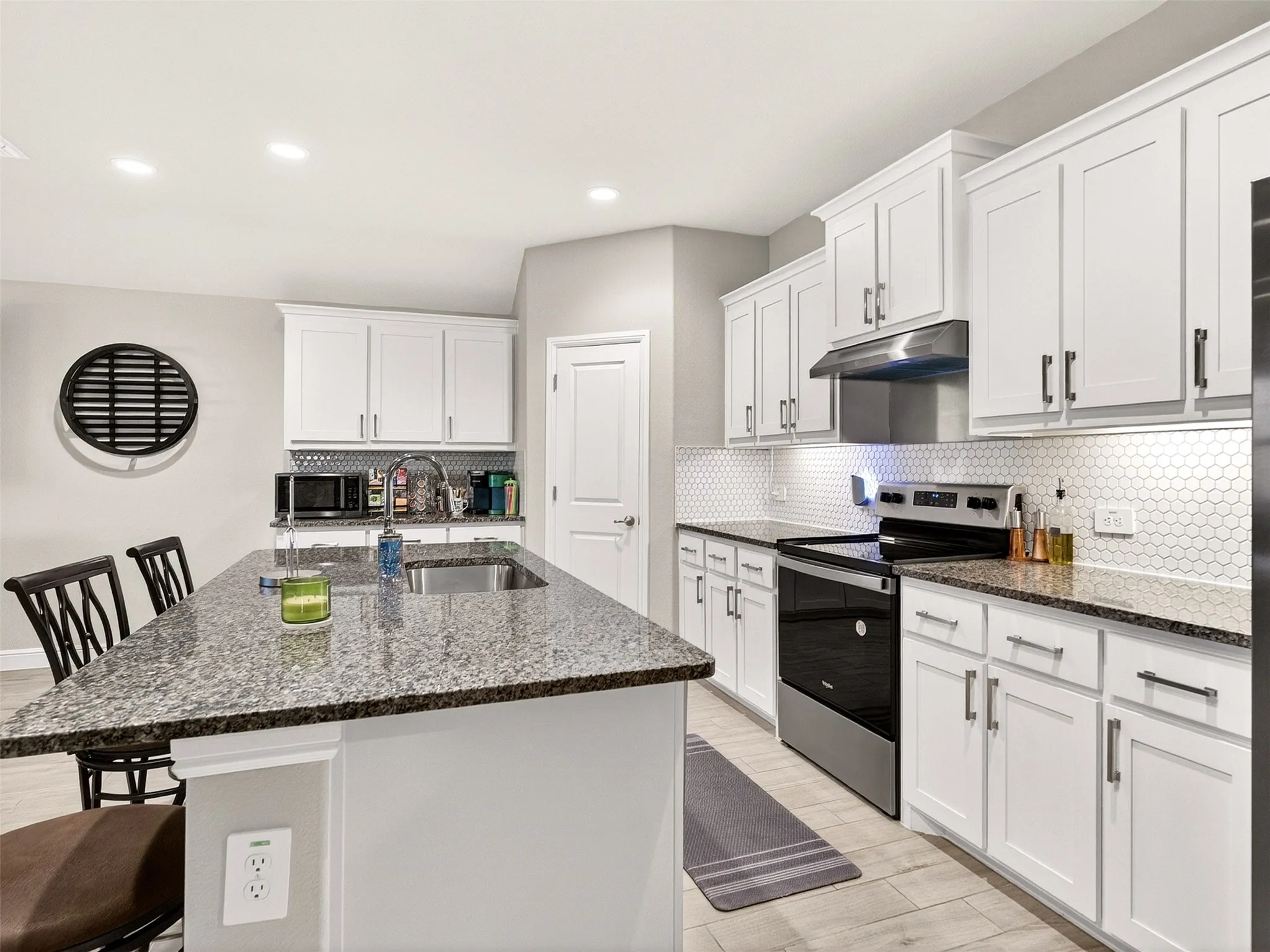 Kitchen featuring white cabinetry, dark speckled countertops, stainless steel appliances, a white hexagonal tile backsplash, and recessed lighting