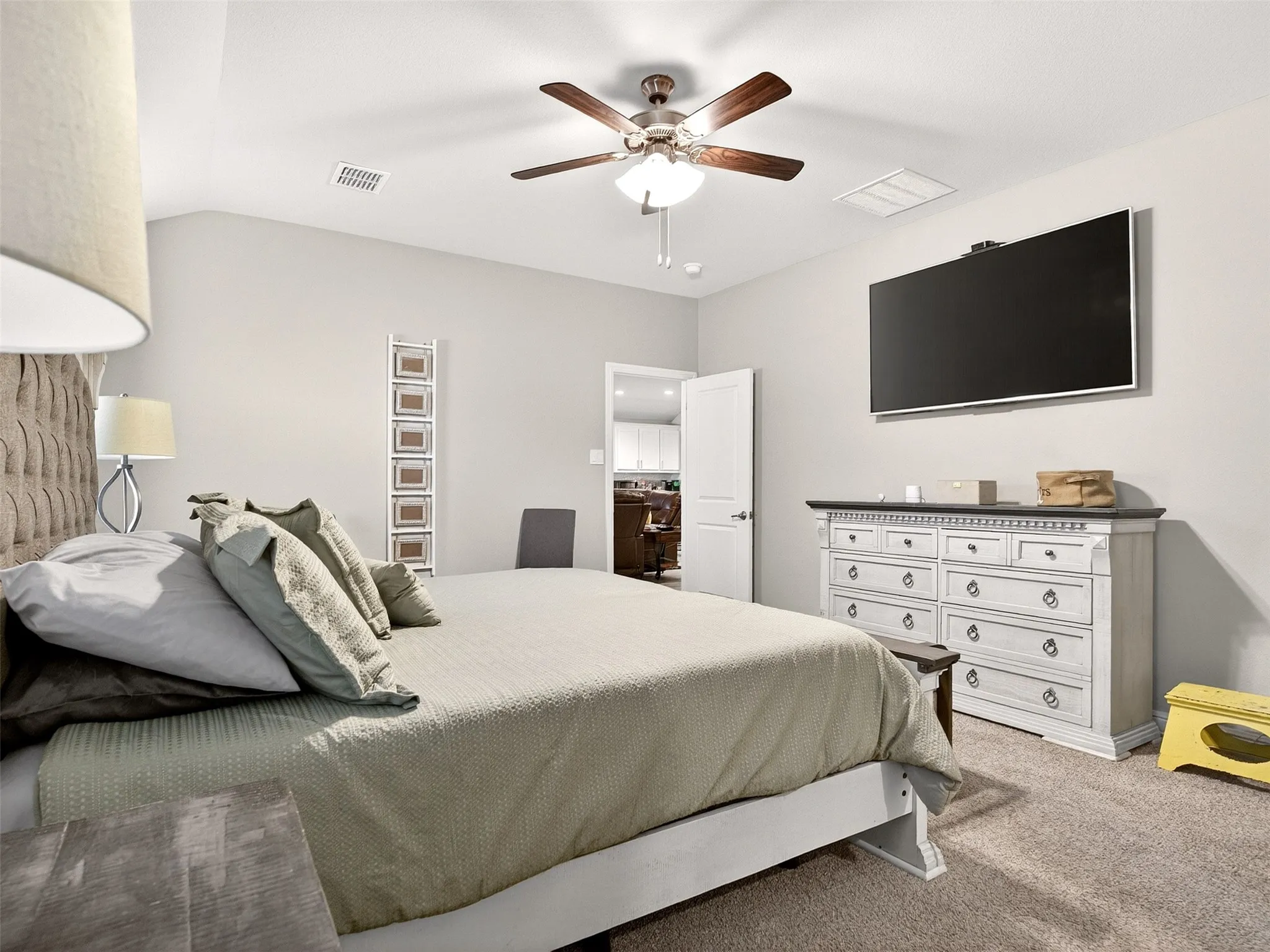 Carpeted flooring, vaulted ceiling, ceiling fan with integrated lighting, and a white paneled door
