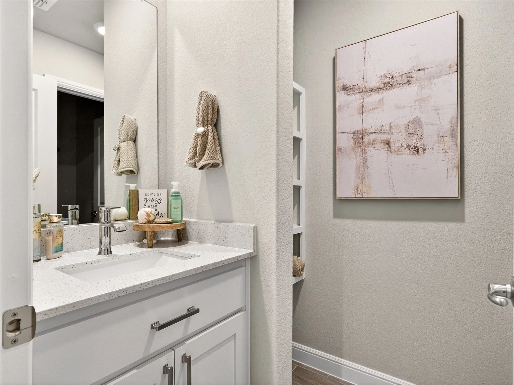 White vanity with polished chrome hardware, integrated rectangular sink, and light-toned countertop