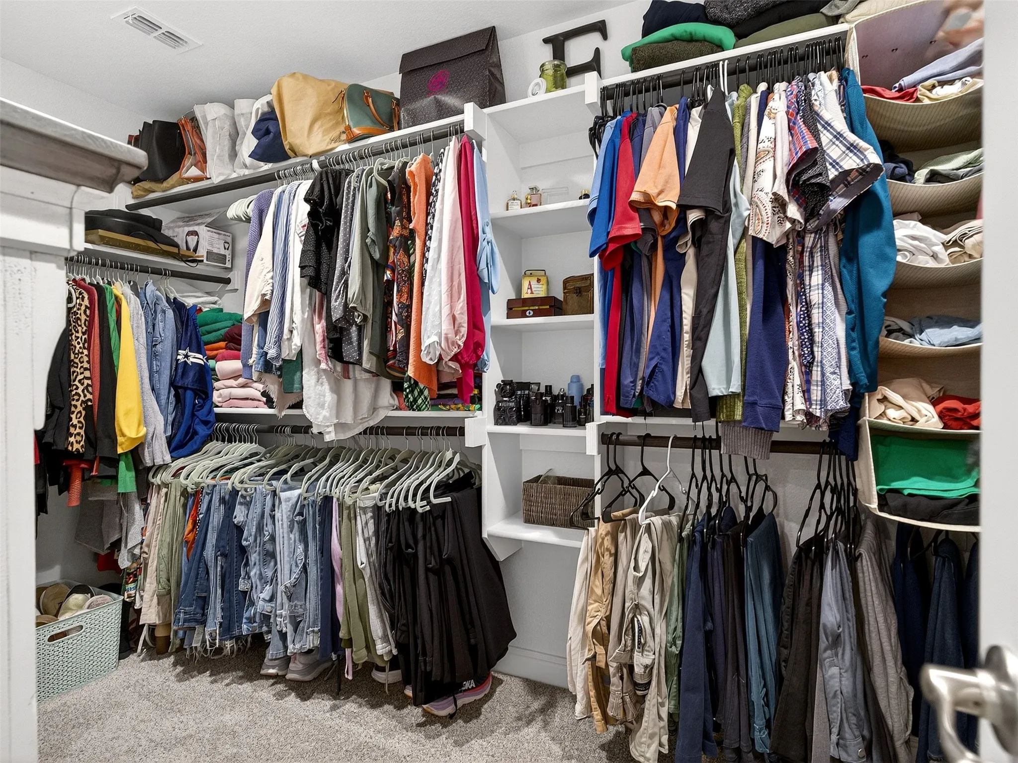 Custom closet system featuring multiple hanging rods, integrated shelving, and carpeted flooring