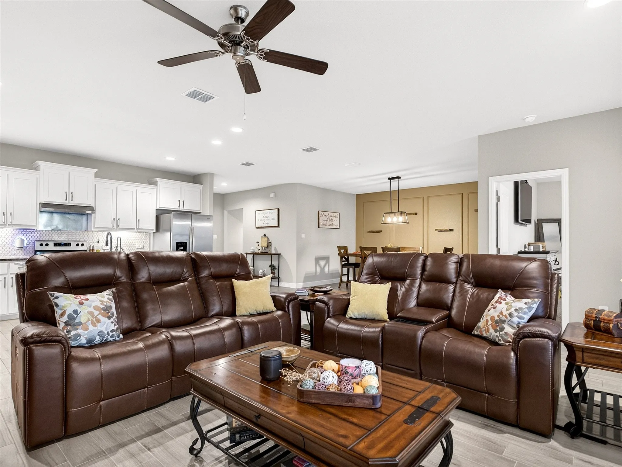 Recessed lighting, wood-finish flooring, ceiling fan, white cabinetry, and stainless steel appliances
